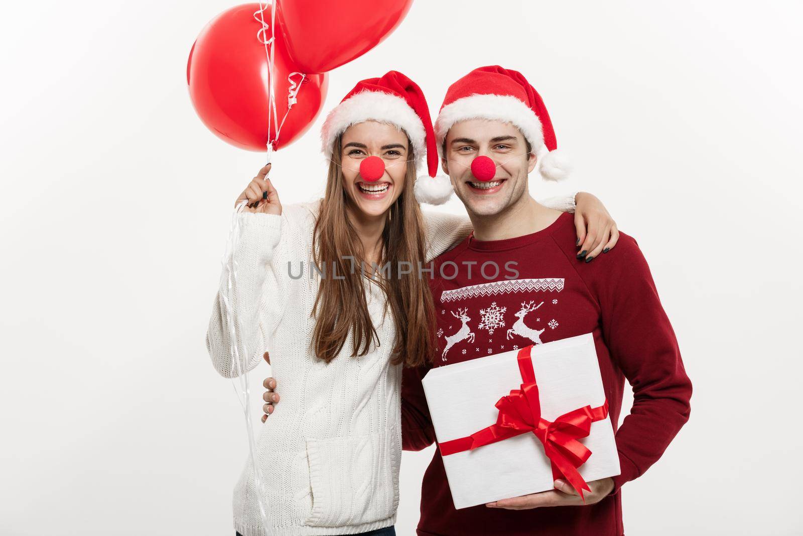 Christmas Concept - Young caucasian couple holding gifts,champnage and balloon making funny face on Christmas.