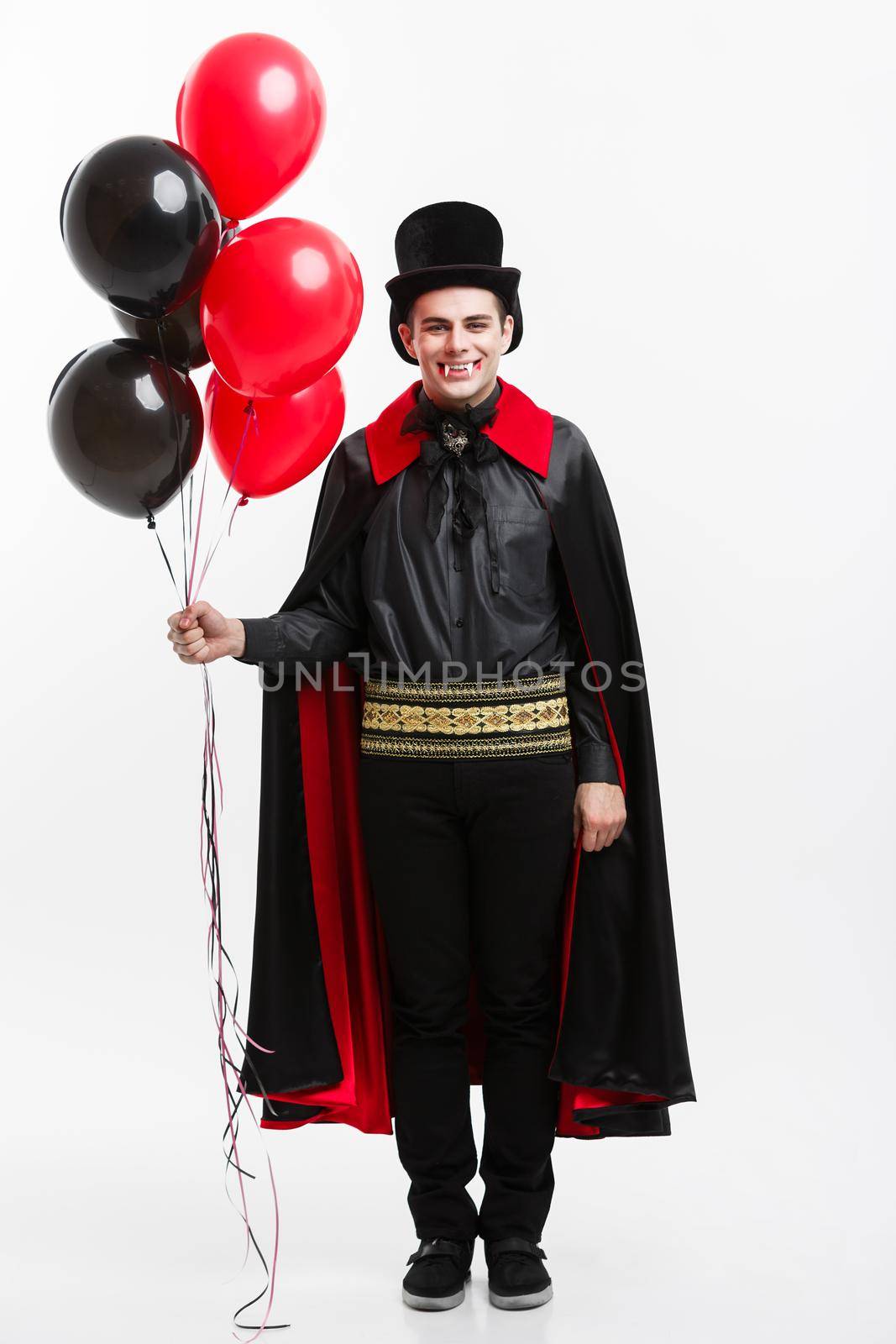 Vampire Halloween Concept - Full-lenght Portrait of handsome caucasian Vampire in black and red halloween costume.