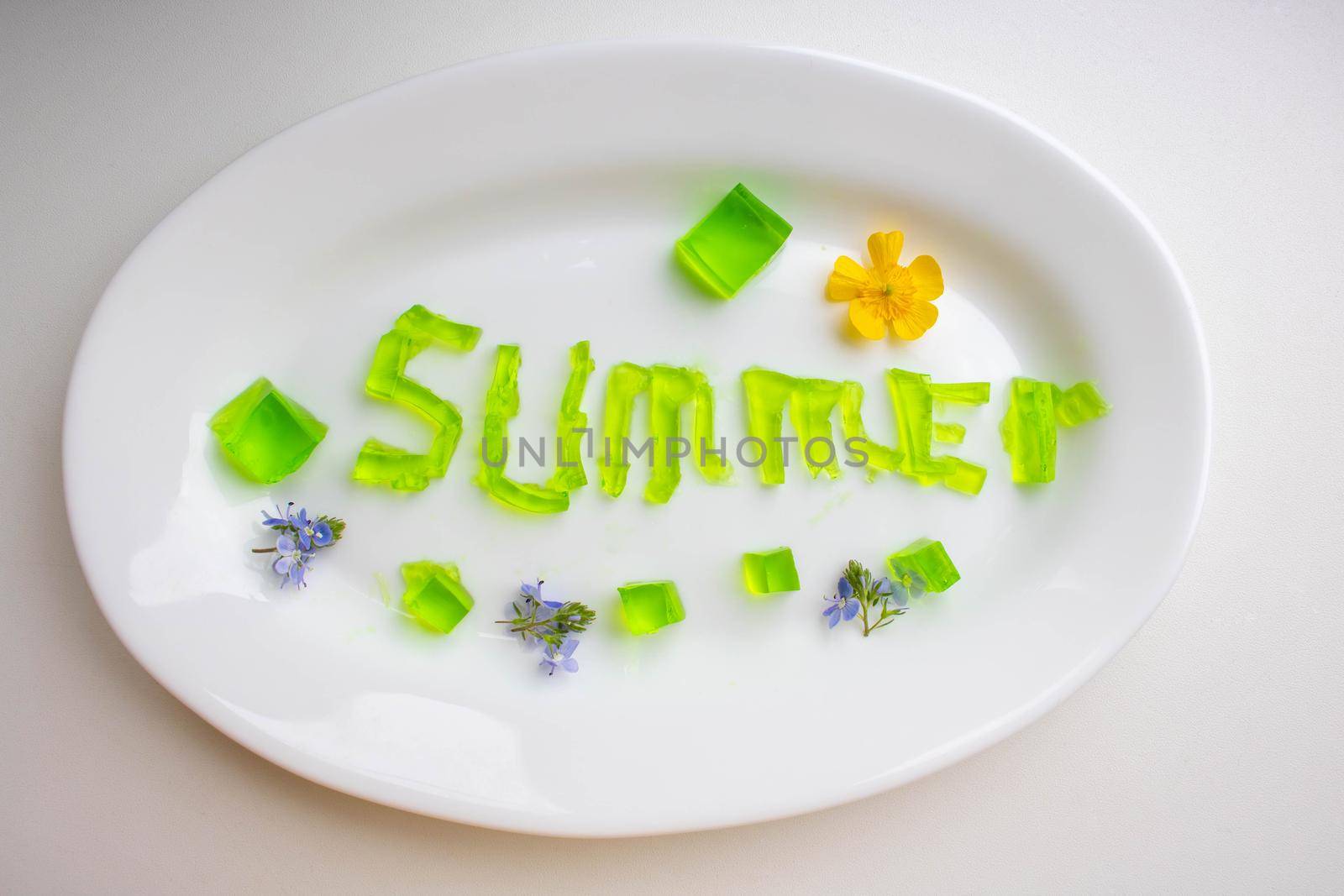 The word summer is made of green jelly cubes on a white plate.
