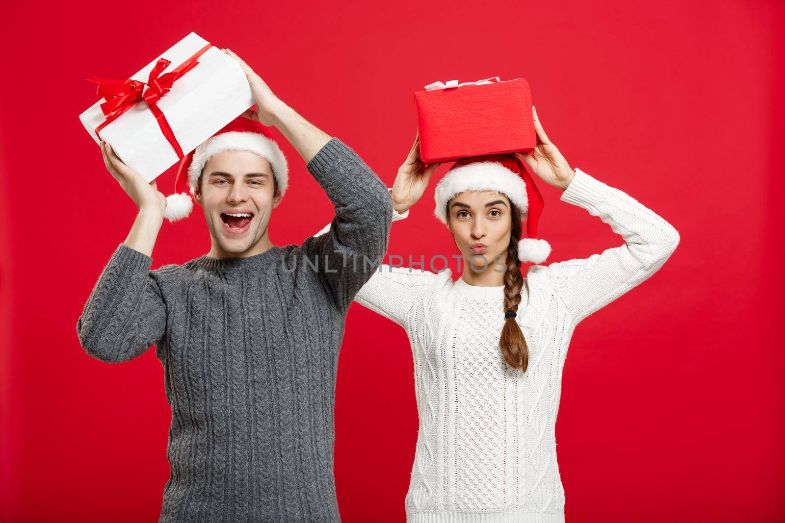 Christmas Concept - portrait young couple in Christmas sweater enjoy playing with gifts by Benzoix