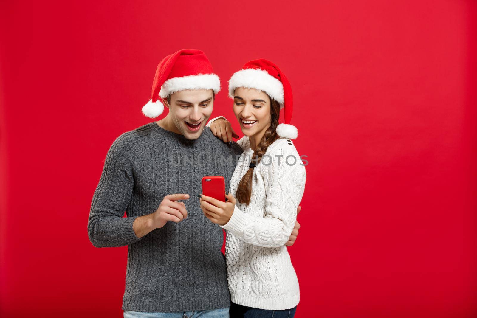 Christmas Concept - Young handsome and beautiful couple enjoy checking on mobile phone in christmas day by Benzoix