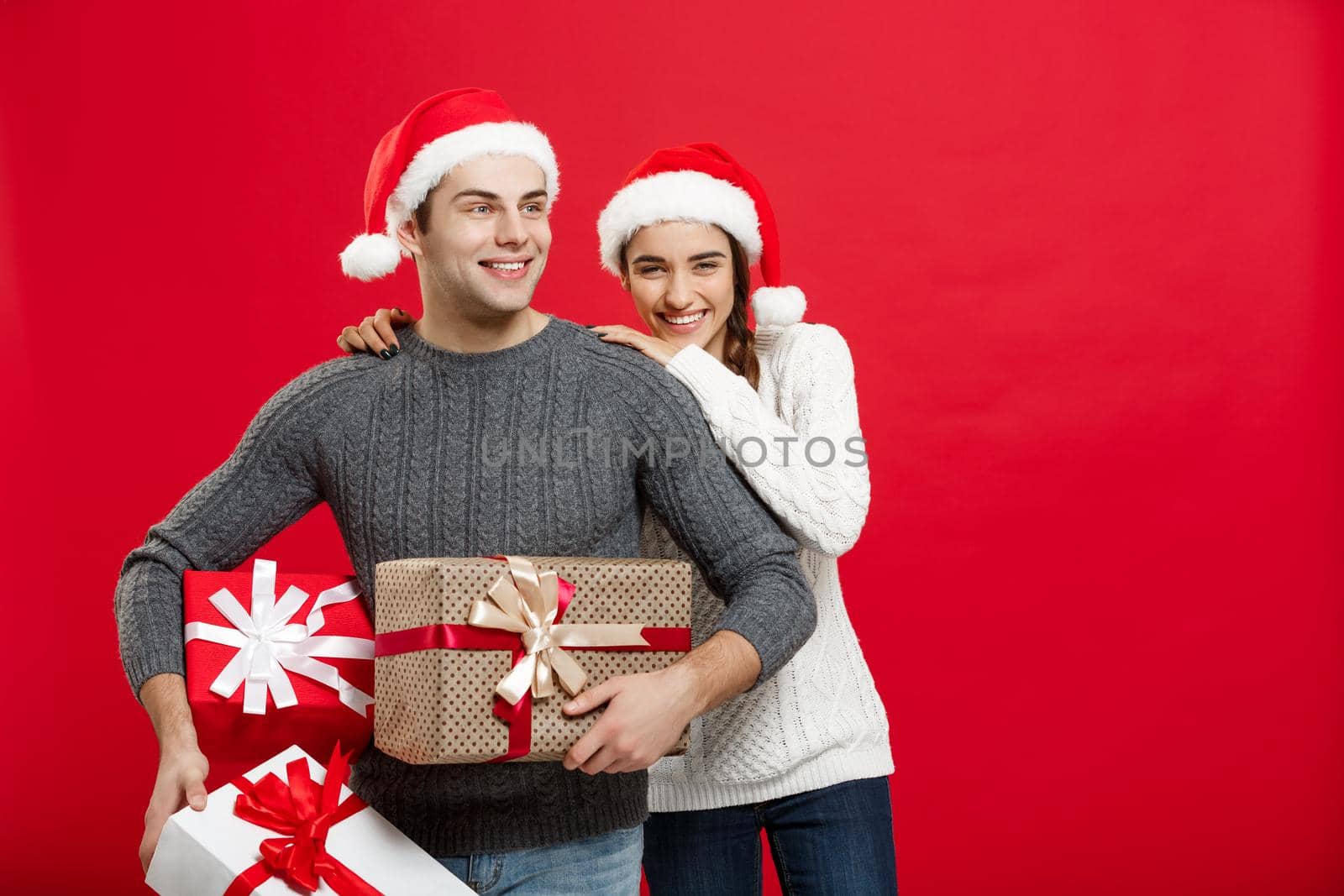 Christmas Concept - Young attractive couple holding a lot of presents enjoy shopping and celebrating in Christmas day by Benzoix