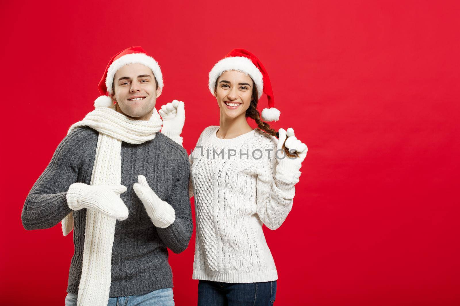 Christmas concept - Happy young couple in sweatesr celebrating christmas with playing and dancing by Benzoix