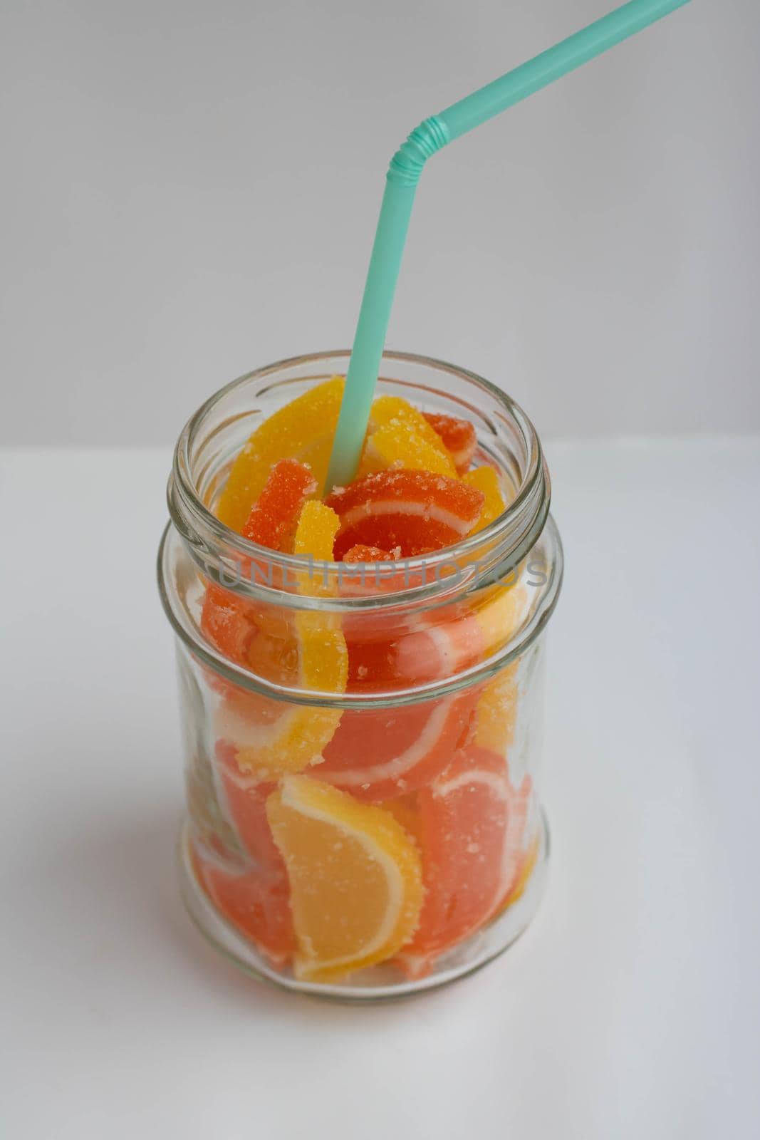 Dessert marmalade in the form of slices of lemon and orange in a jar. Sweet yellow and orange jelly candies