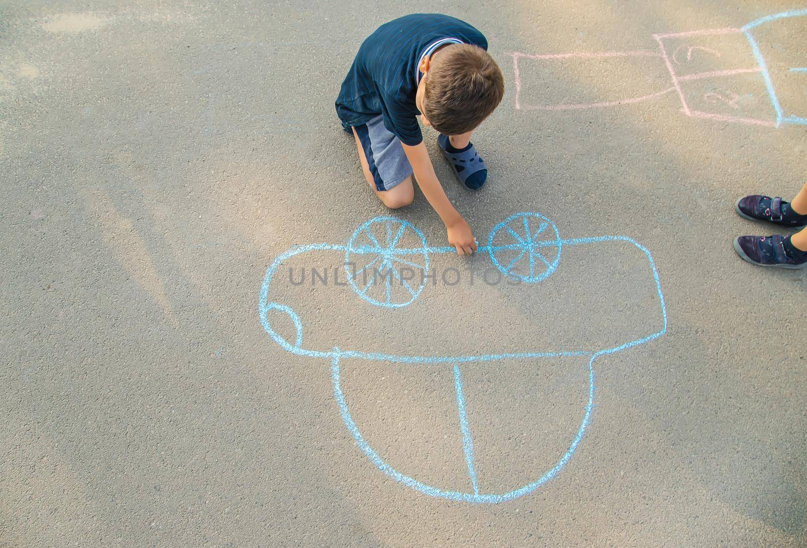 children draw a car with chalk on the pavement. selective focus. nature.
