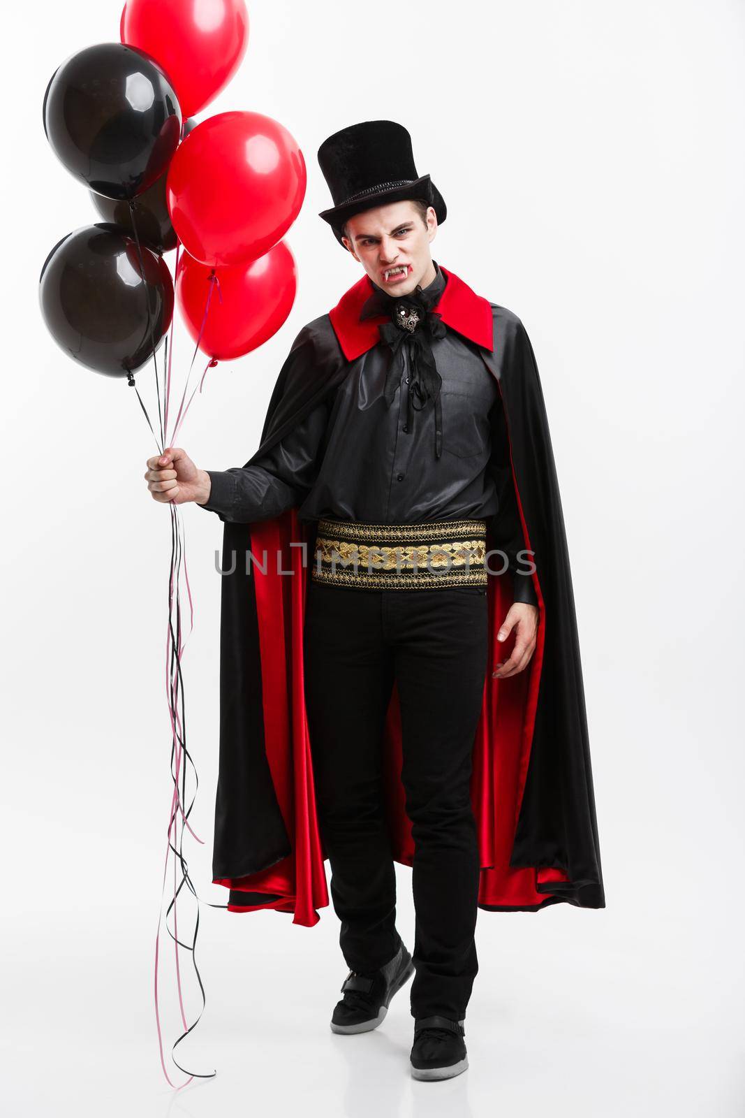 Vampire Halloween Concept - Full-lenght Portrait of handsome caucasian Vampire in black and red halloween costume.