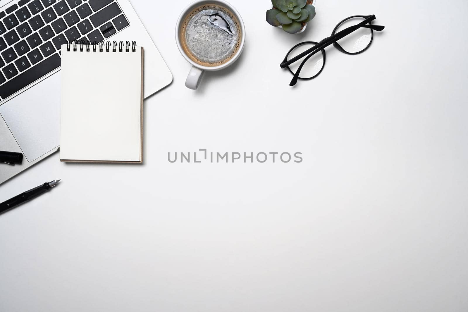 Simple workplace with laptop computer, coffee cup, glasses and notebook. Top view, flat lay, copy space.