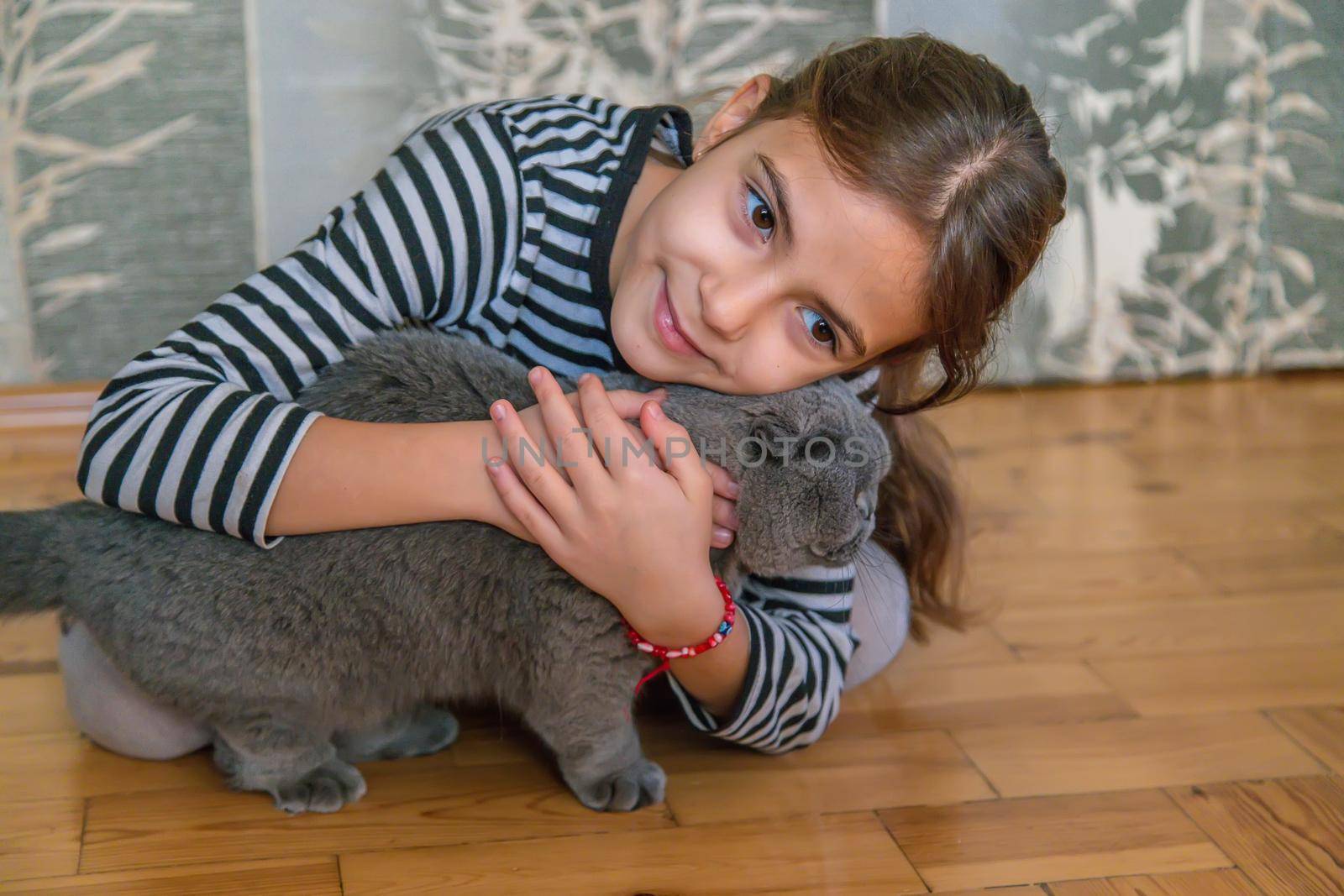 Child girl at home with a cat. Selective focus. Kid.