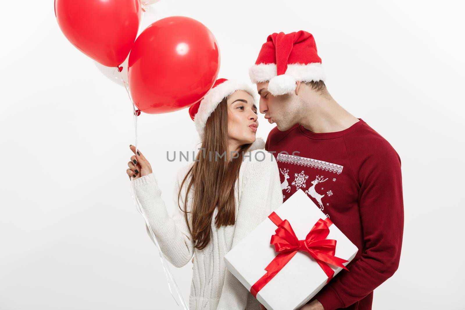 Christmas Concept - Young girlfriend holding balloon is hugging and playing with her boyfriend doing a surprise on Christmas.