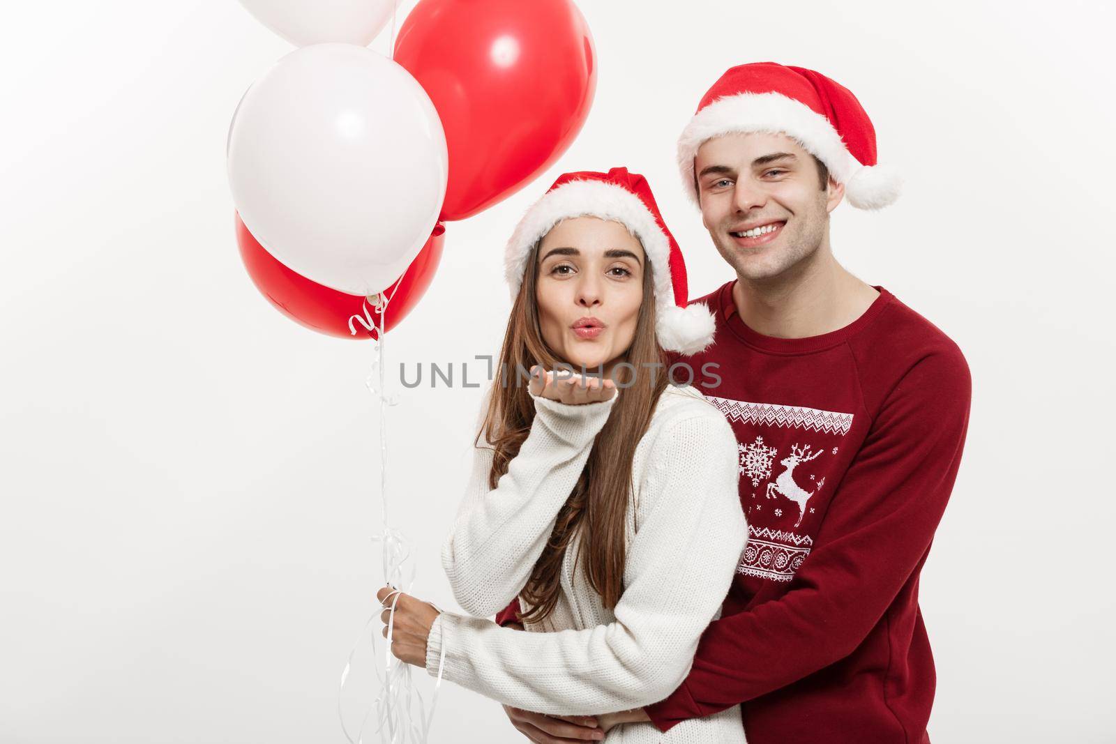 Christmas Concept - Young girlfriend holding balloon is hugging and playing with her boyfriend doing a surprise on Christmas.