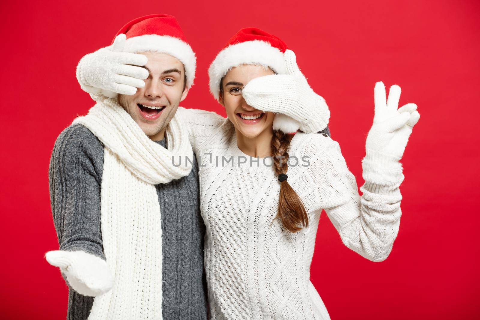 Christmas Concept - Young happy stylish couple in winter clothes close eyes each others celebrating in Christmas day.