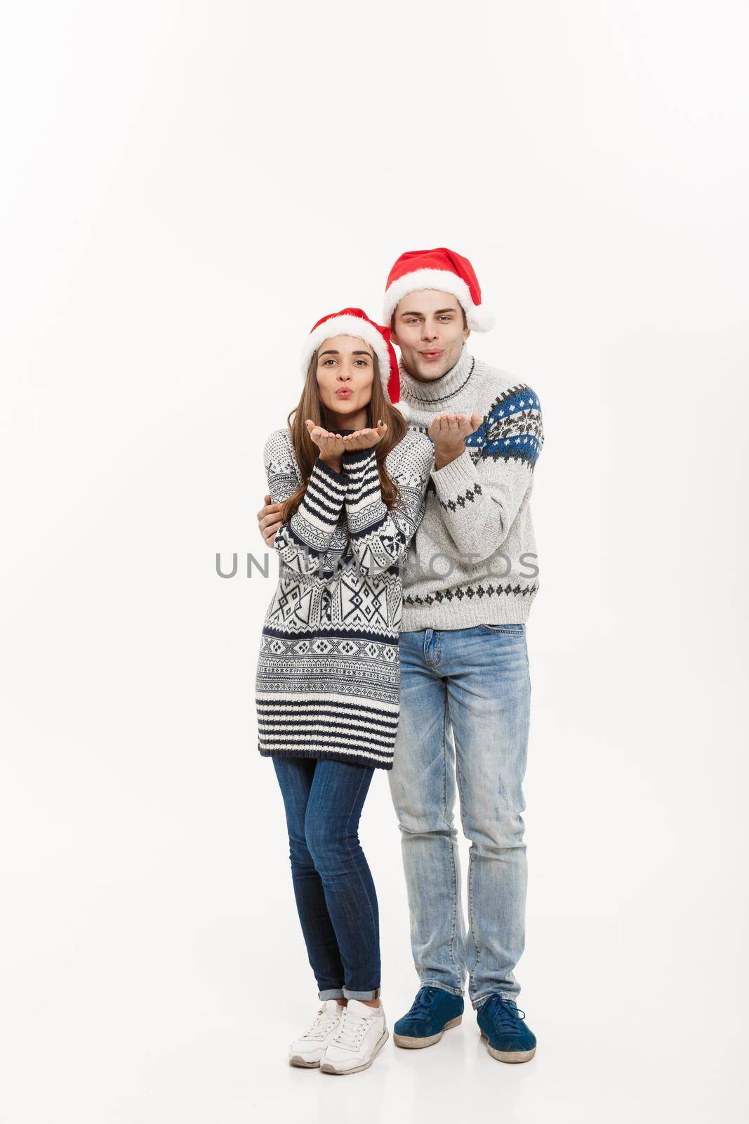Christmas concept - Full-length Young attractive caucasian couple giving a kiss celebrating for Christmas day. by Benzoix