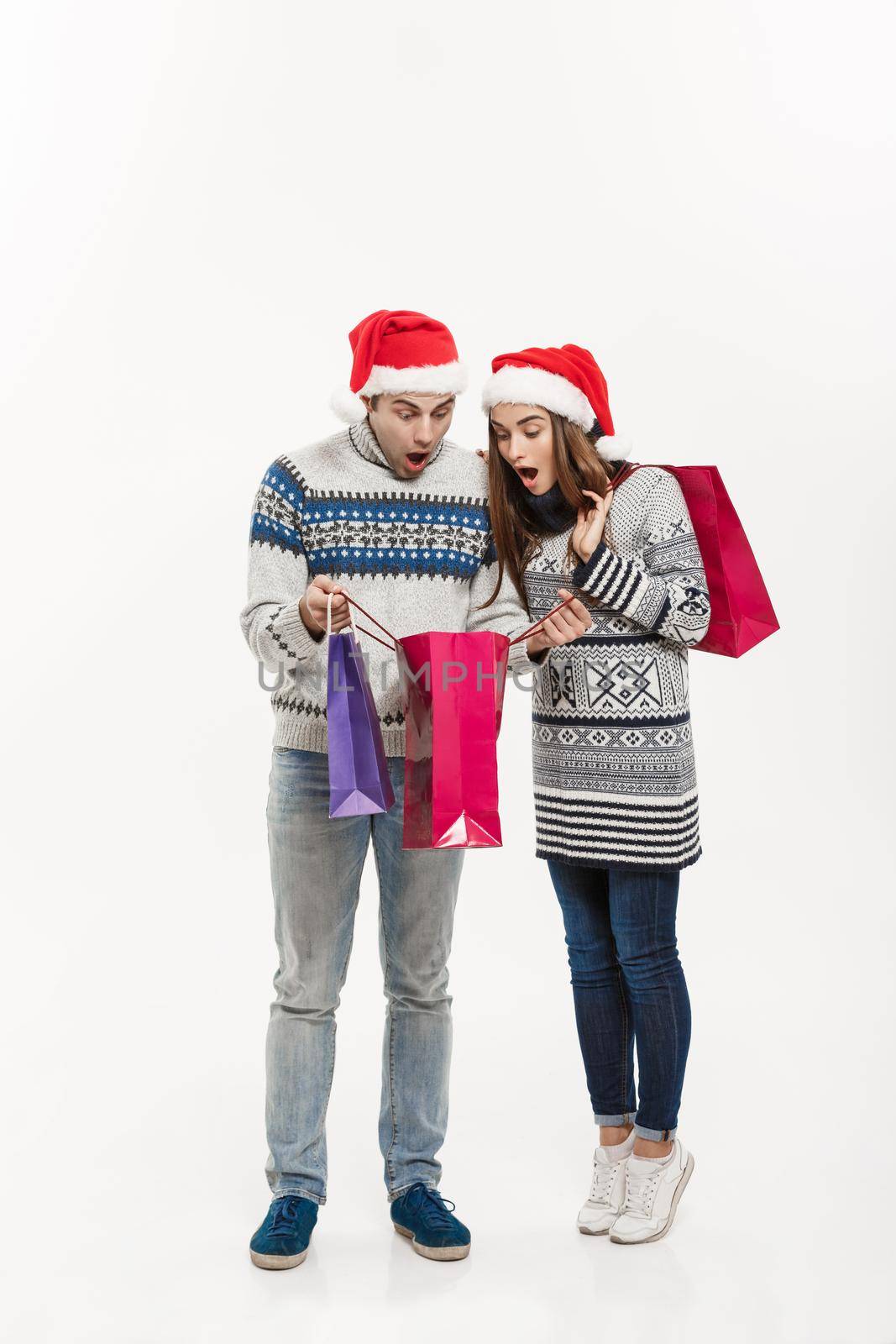 Christmas Concept - Full length Young attractive couple holding shopping bags isolated on white grey background