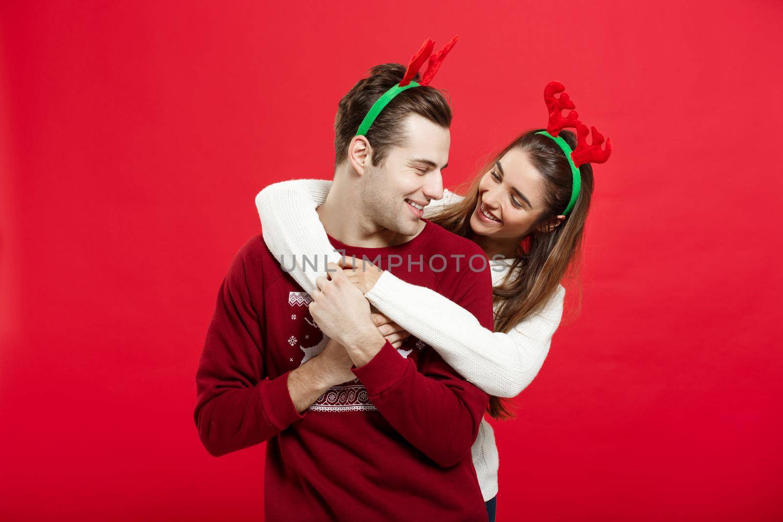 Christmas Concept - Romantic couple in a christmas sweaters huging each other by Benzoix