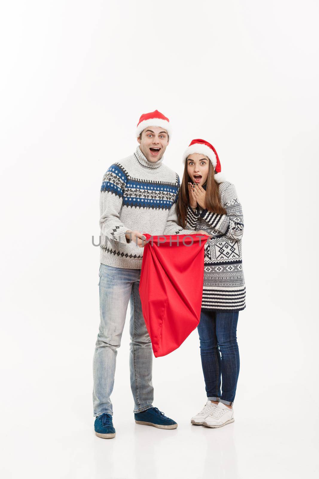 Christmas Concept - Full length Young attractive couple holding santa bag isolated on white grey background. by Benzoix