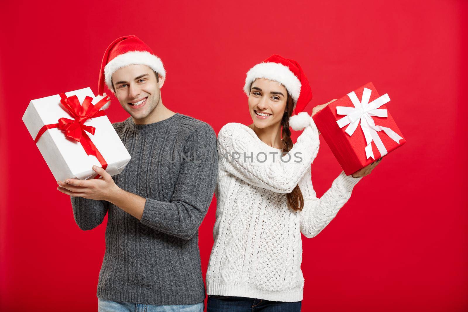 Christmas Concept - Young attractive couple giving gifts to each other celebrating in Christmas day.