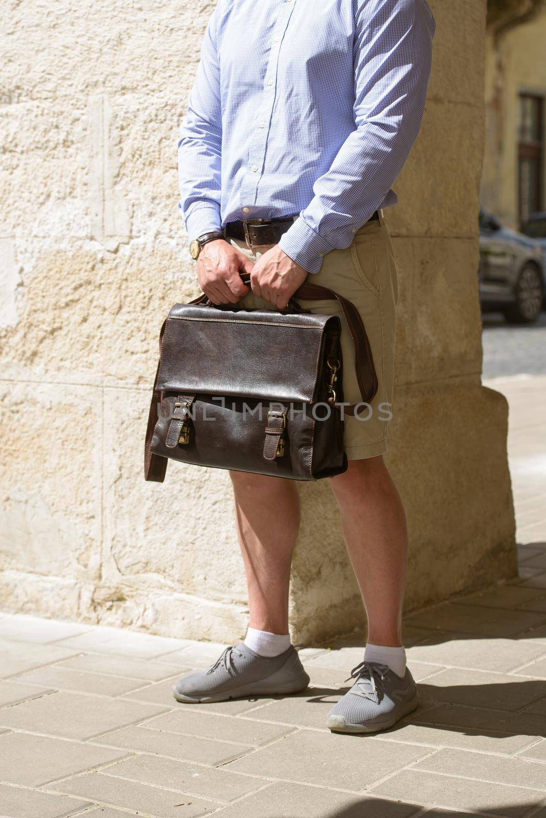 Part photo of a man with a brown leather briefcase with antique and retro look. Outdoors photo by Ashtray25