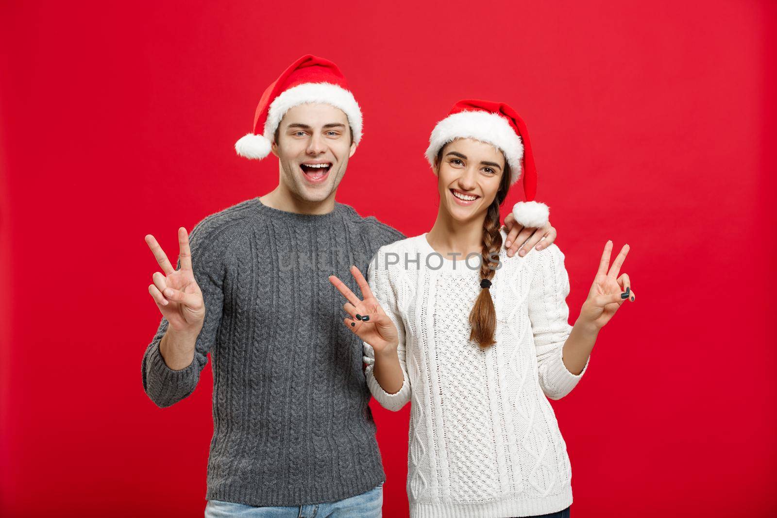 Christmas Concept - portrait lovely young couple showing two finger gesture with finger to camera.