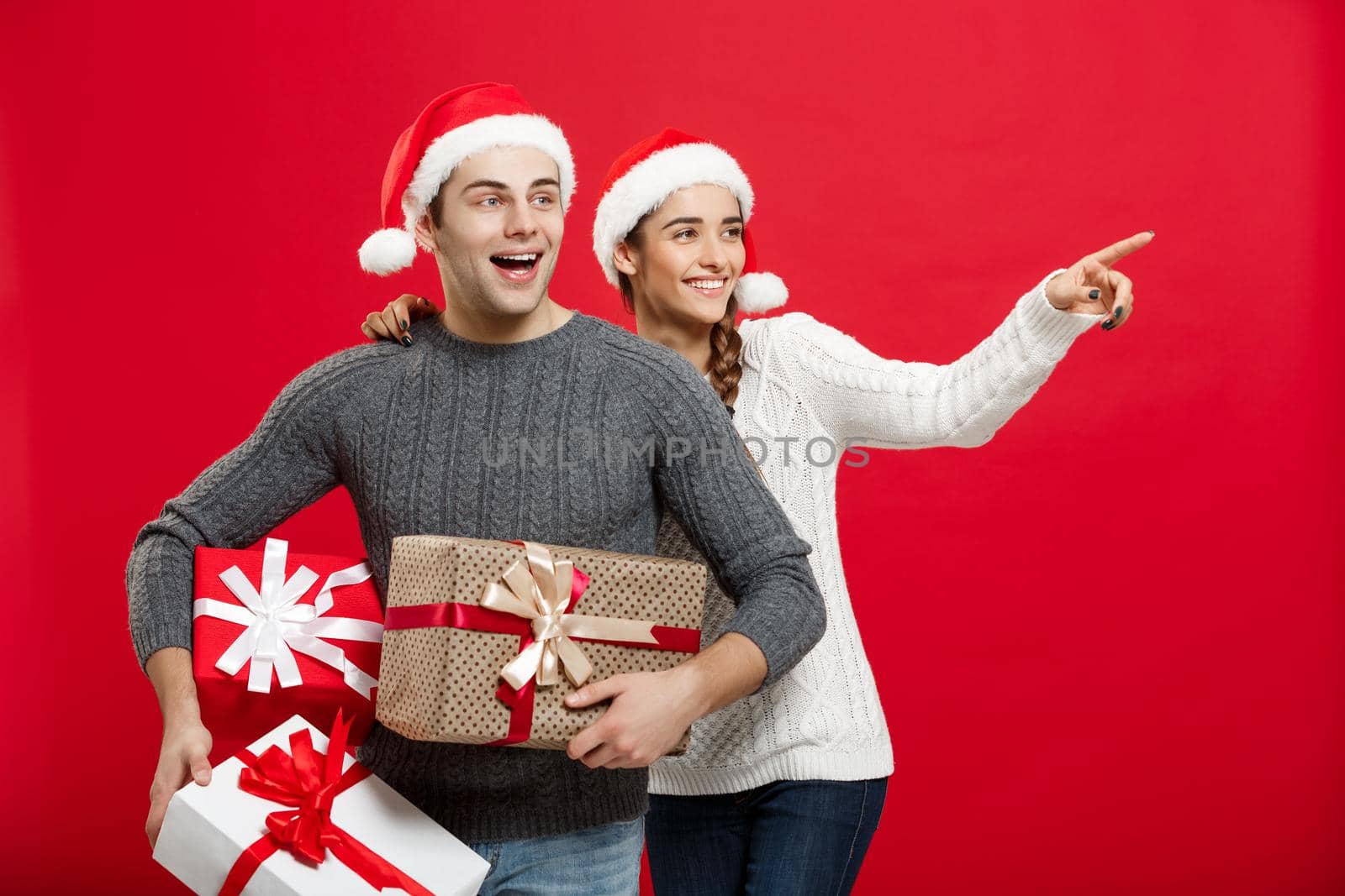 Christmas Concept - Young attractive couple holding a lot of presents enjoy shopping and celebrating in Christmas day by Benzoix