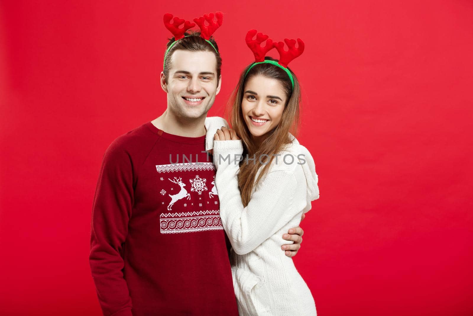 Portrait of a happy young couple posing over red studio background.