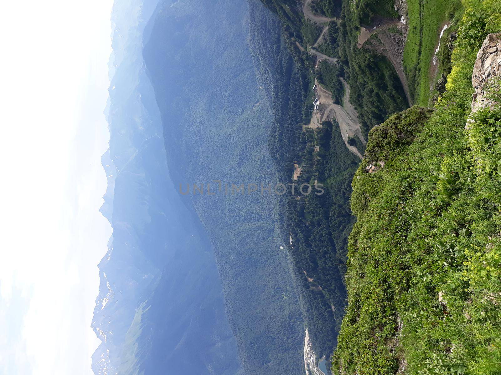 Panoramic mountain landscape with valleys and forested mountain peaks.