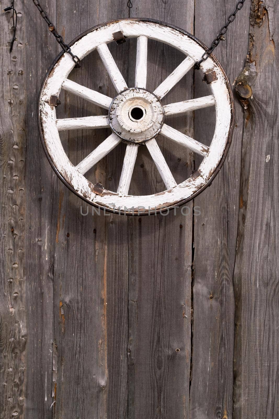An old wooden carriage wheel hanging on the barn wall.