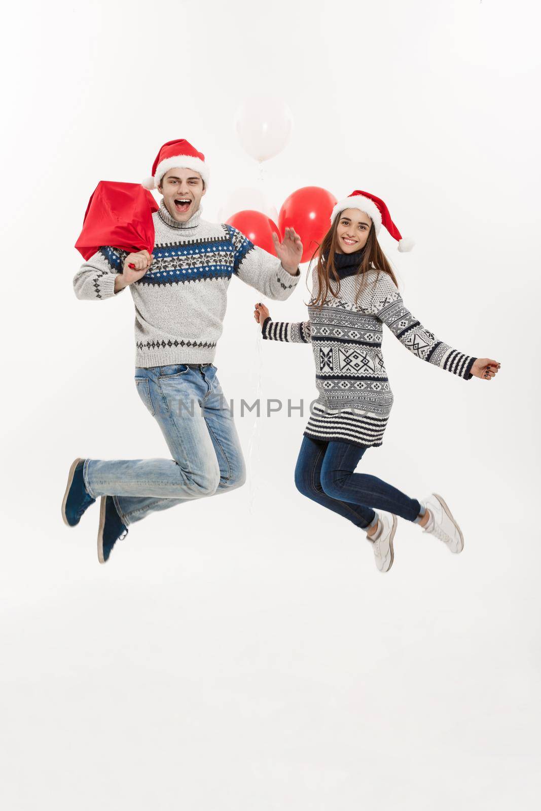 Christmas Concept - Full length Young attractive couple holding santa bag and balloon isolated on white grey background. by Benzoix