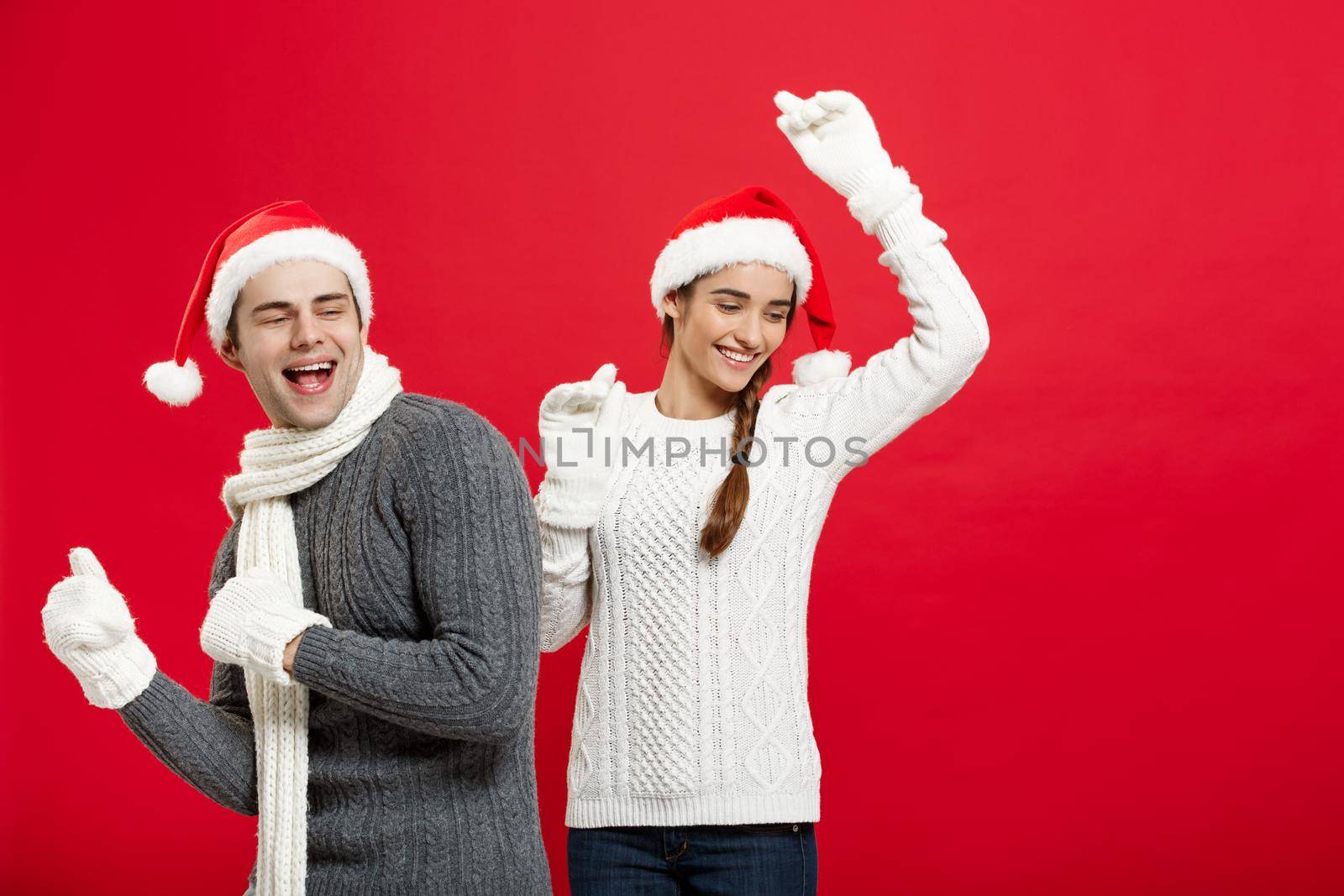 Christmas concept - Happy young couple in sweatesr celebrating christmas with playing and dancing by Benzoix