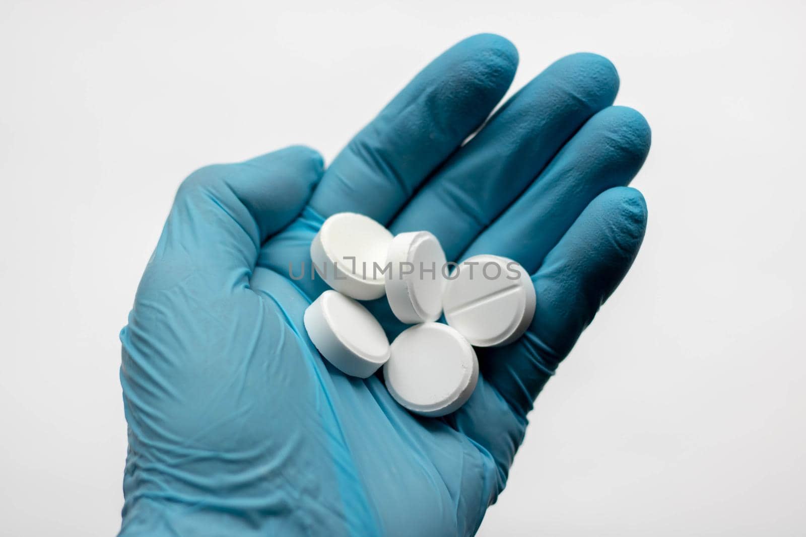 Hand in medical glove with pills on white background.doctor