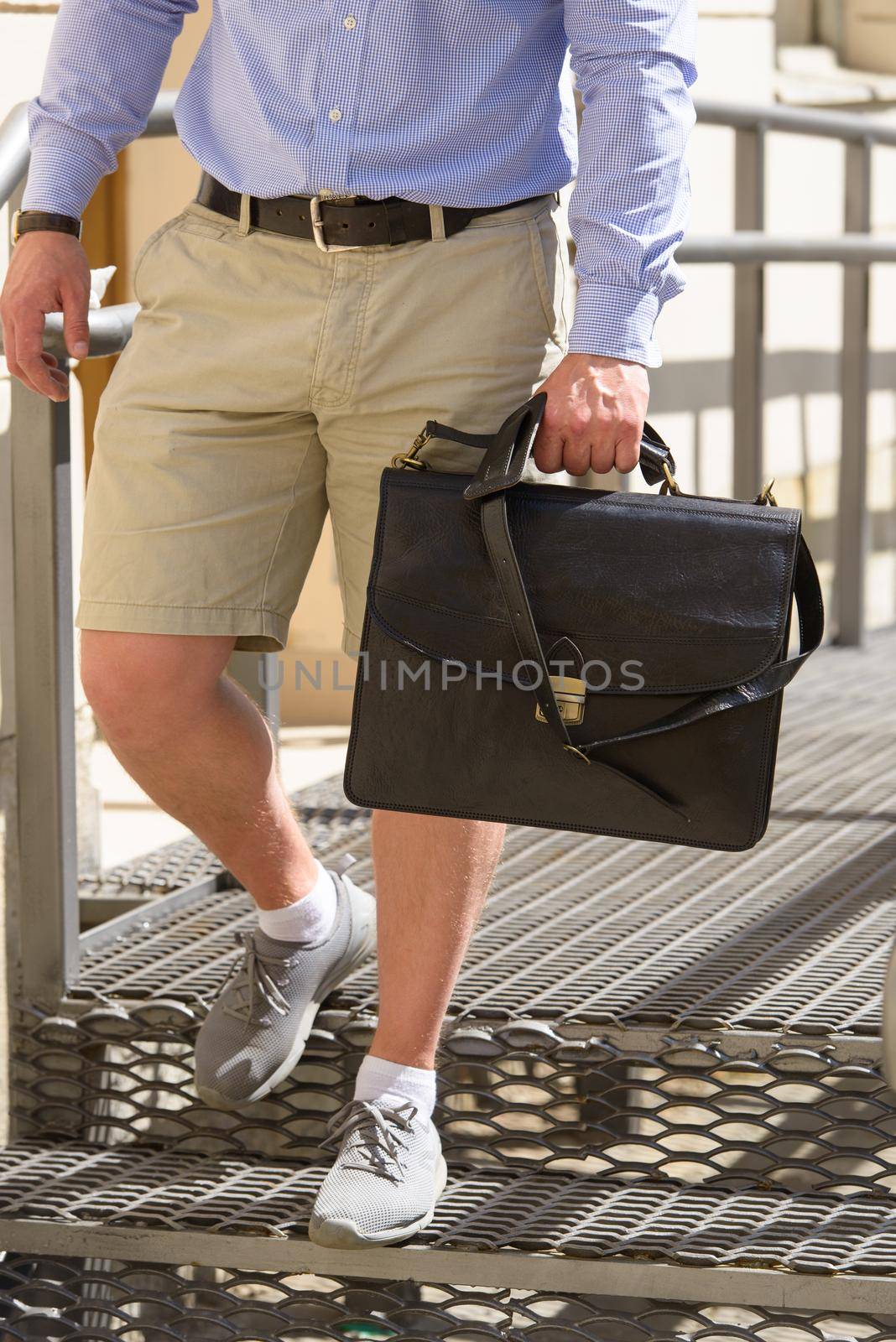 Man with a brown leather briefcase with antique and retro look. Outdoors photo.