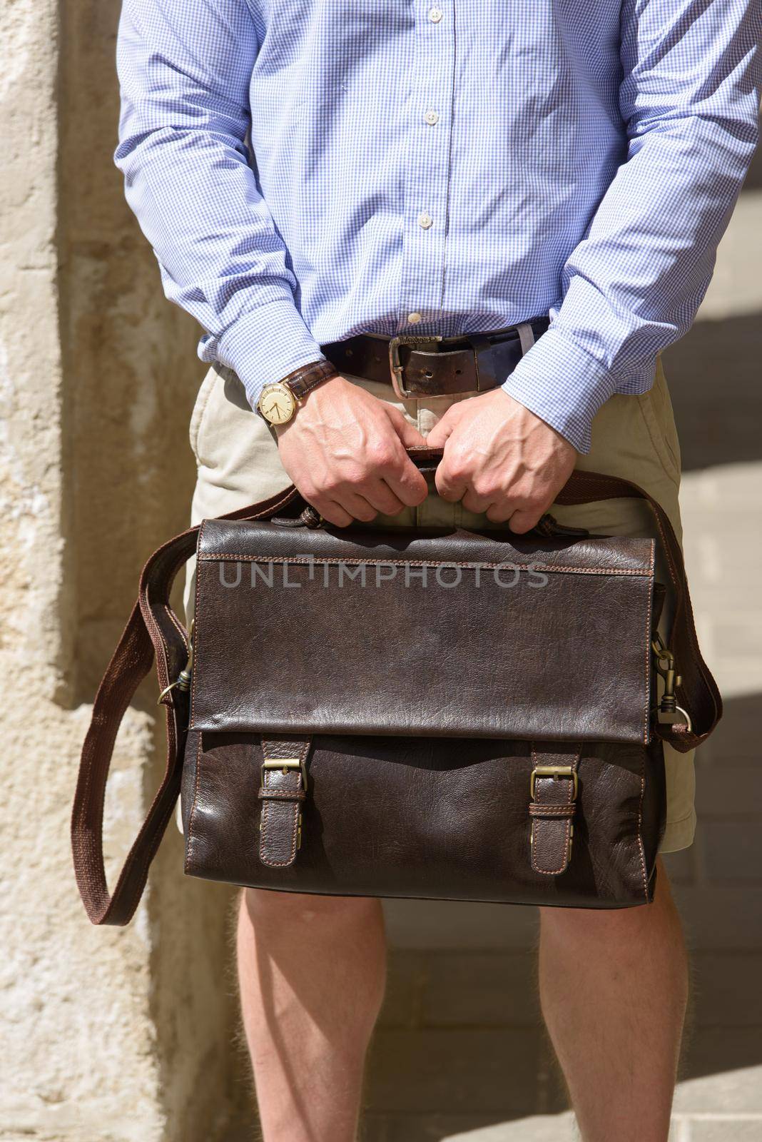 Man with a brown leather briefcase with antique and retro look. Outdoors photo.