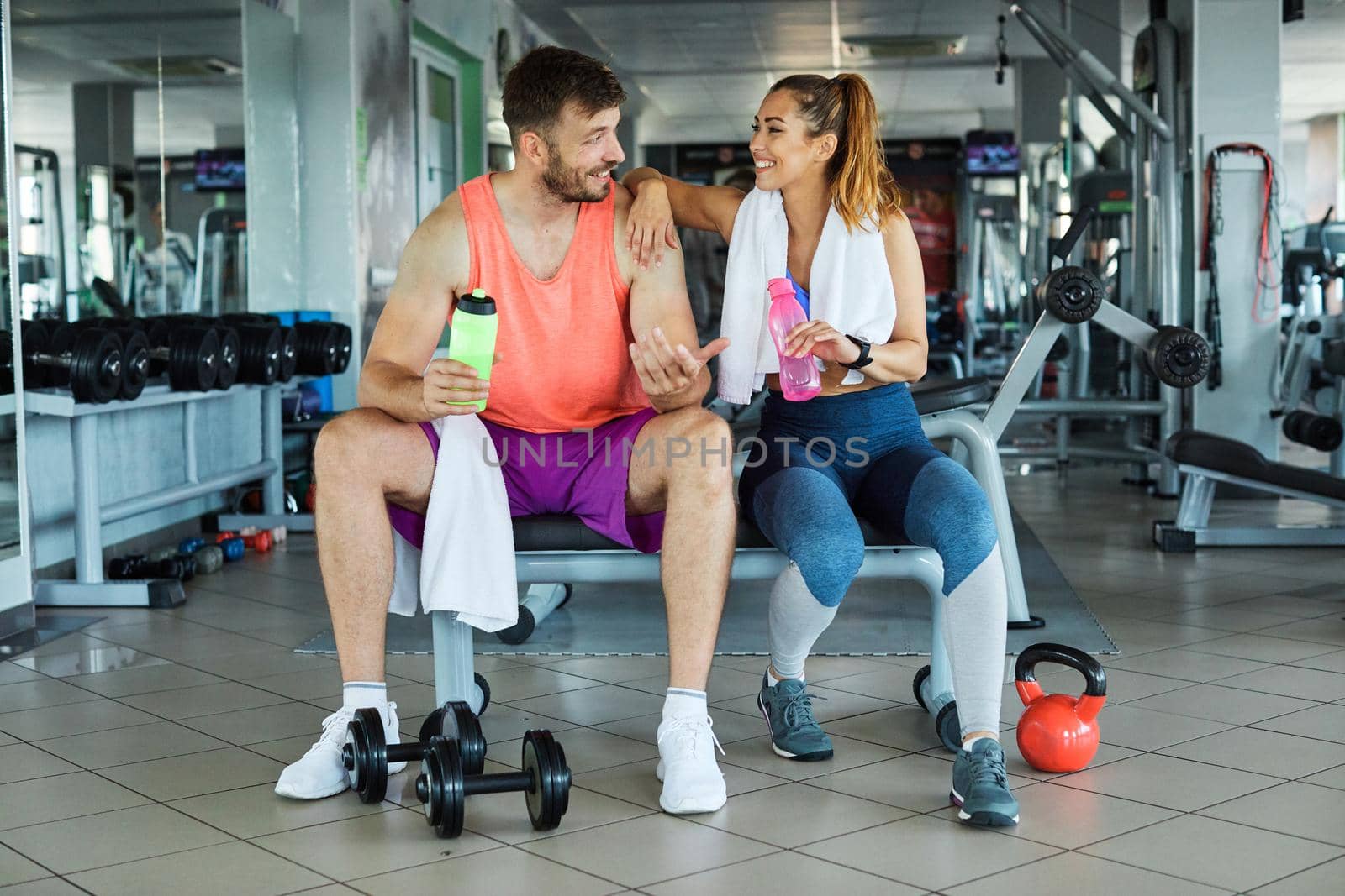 Happy young couple resting after the exercise in the gym