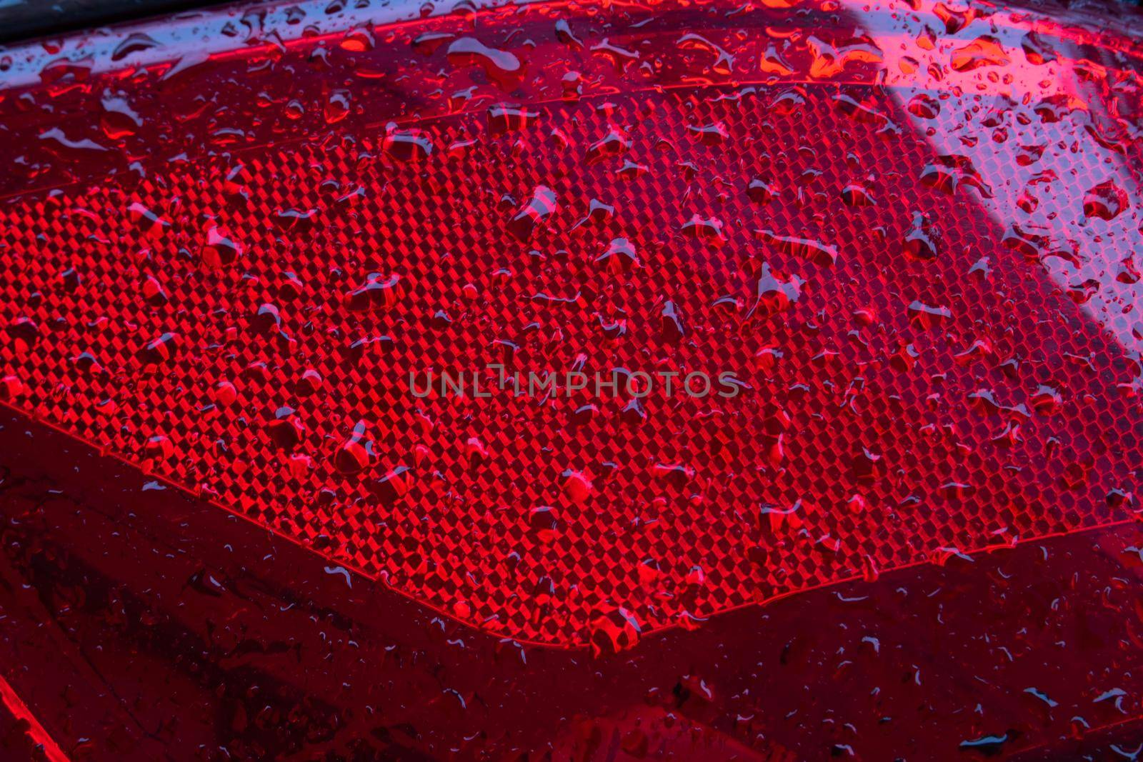 Close-up of the red tail light of a modern car with raindrops.