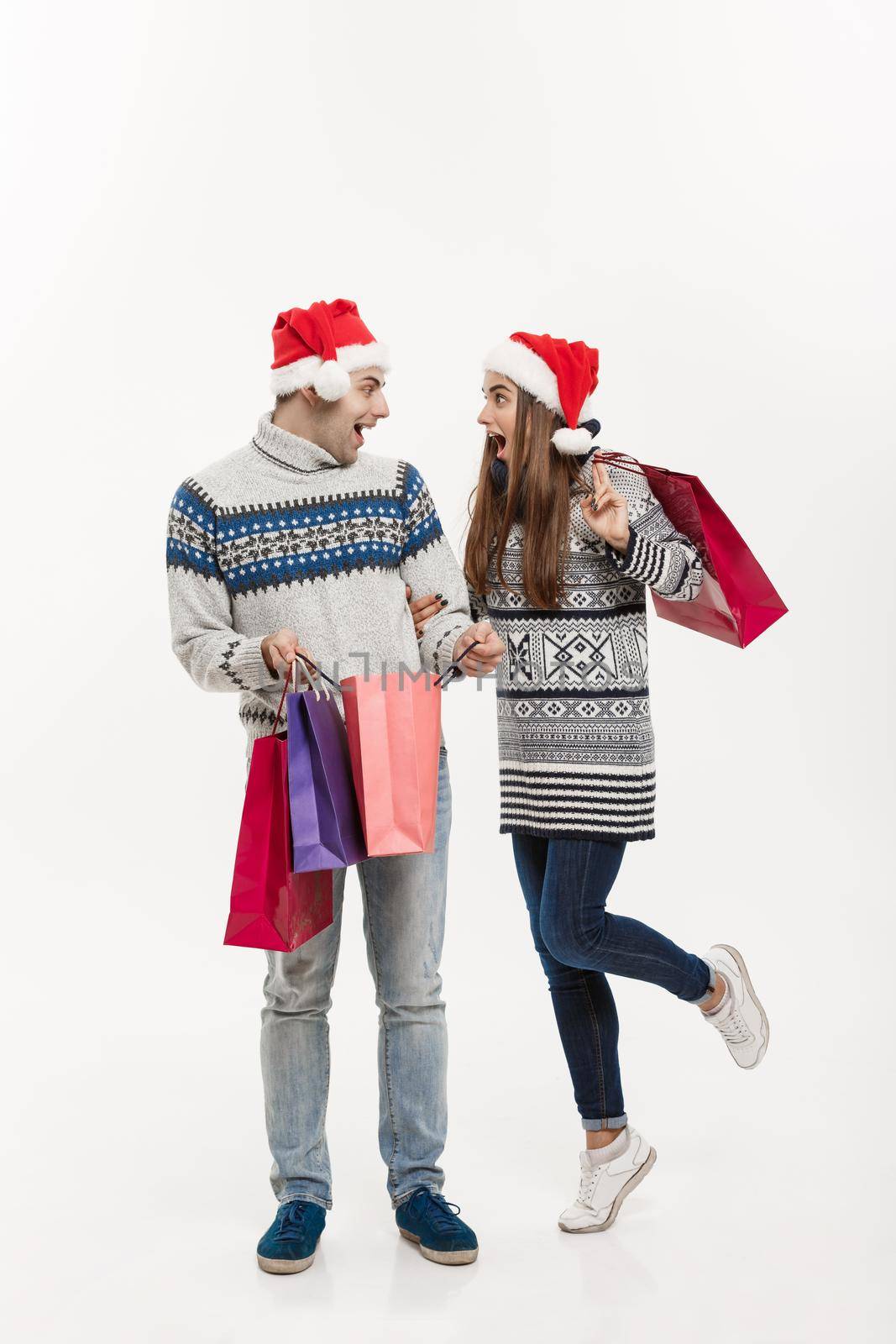 Christmas Concept - Full length Young attractive couple holding shopping bags isolated on white grey background. by Benzoix