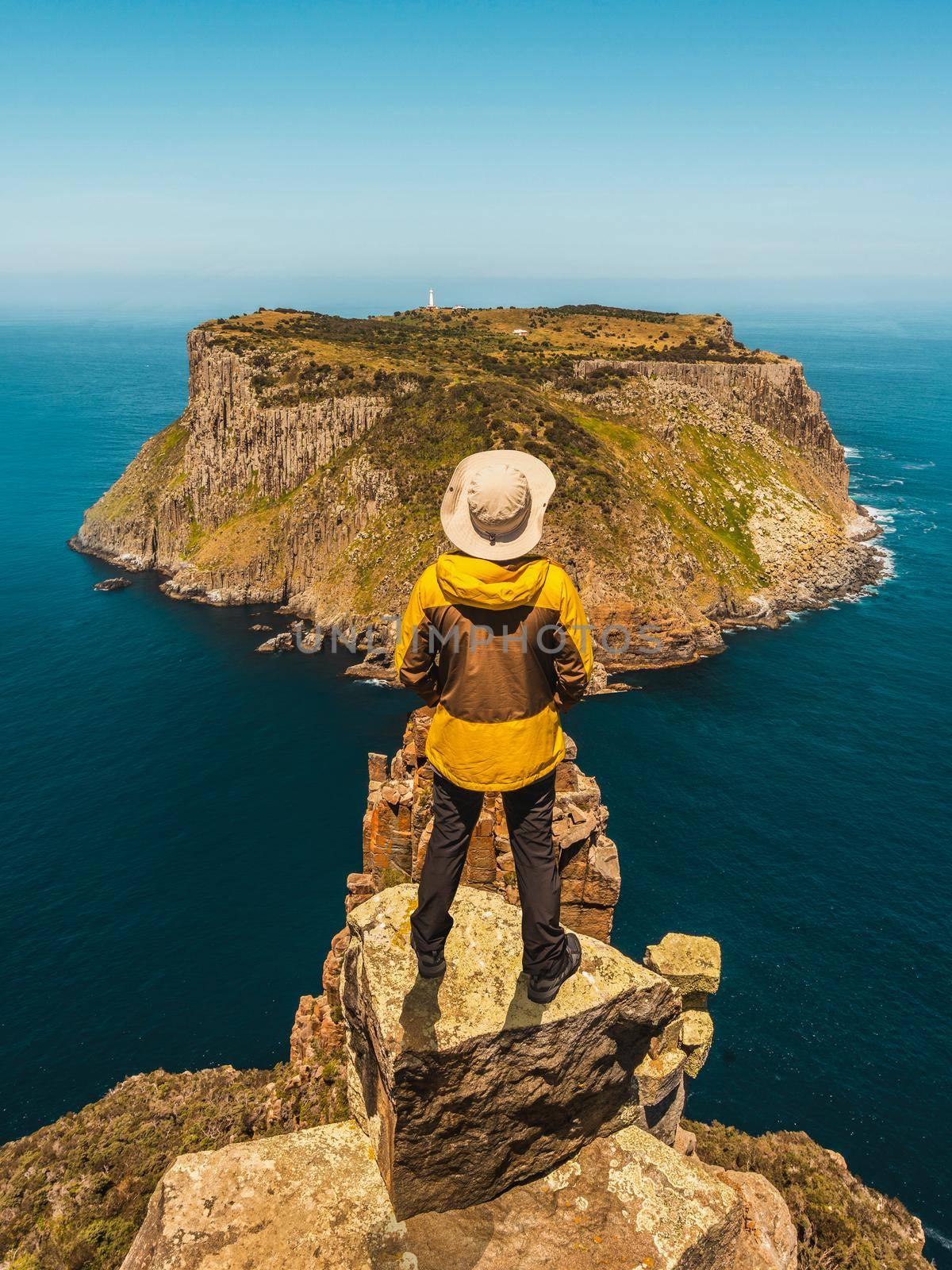 Young man trekker hiking on beautiful coast cliff of Tasman National Park in Tasman peninsula, Three Capes Track near Port Arthur in Tasmania, Australia.