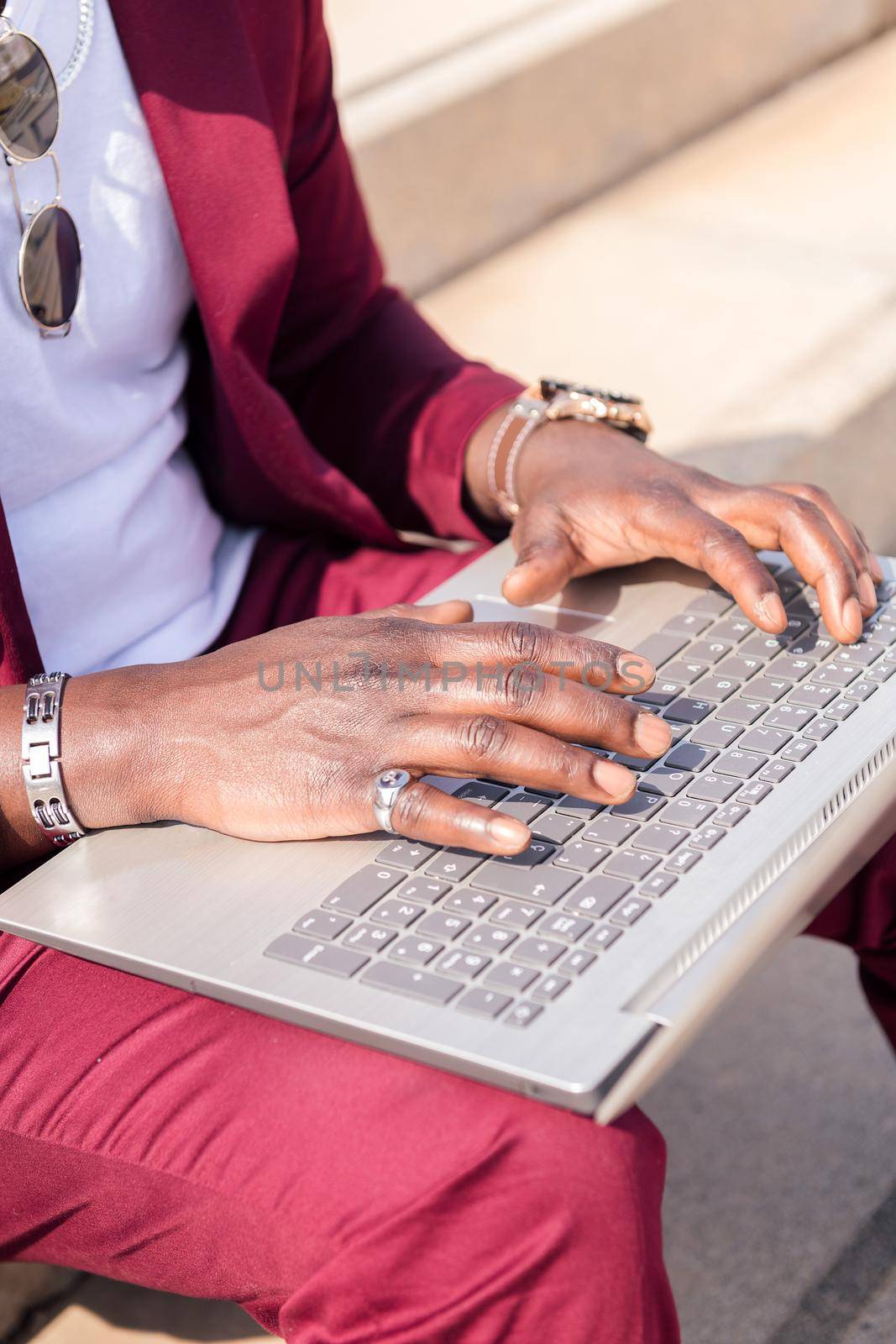 hands of an unrecognizable african man working with his laptop computer sitting on a staircase in the city, concept of technology and remote work