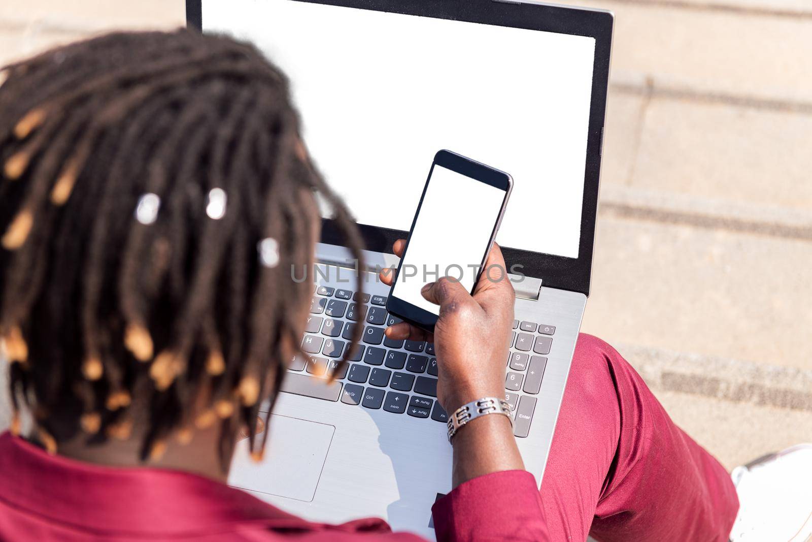 rear view of an unrecognizable black businessman using a smart phone and computer laptop, technology and remote work concept, copy space for text