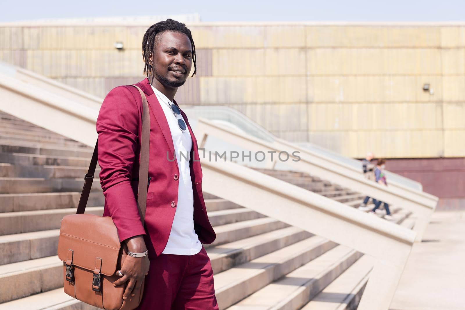 elegant black businessman walking through the city with his briefcase, copy space for text, concept of business and city lifestyle