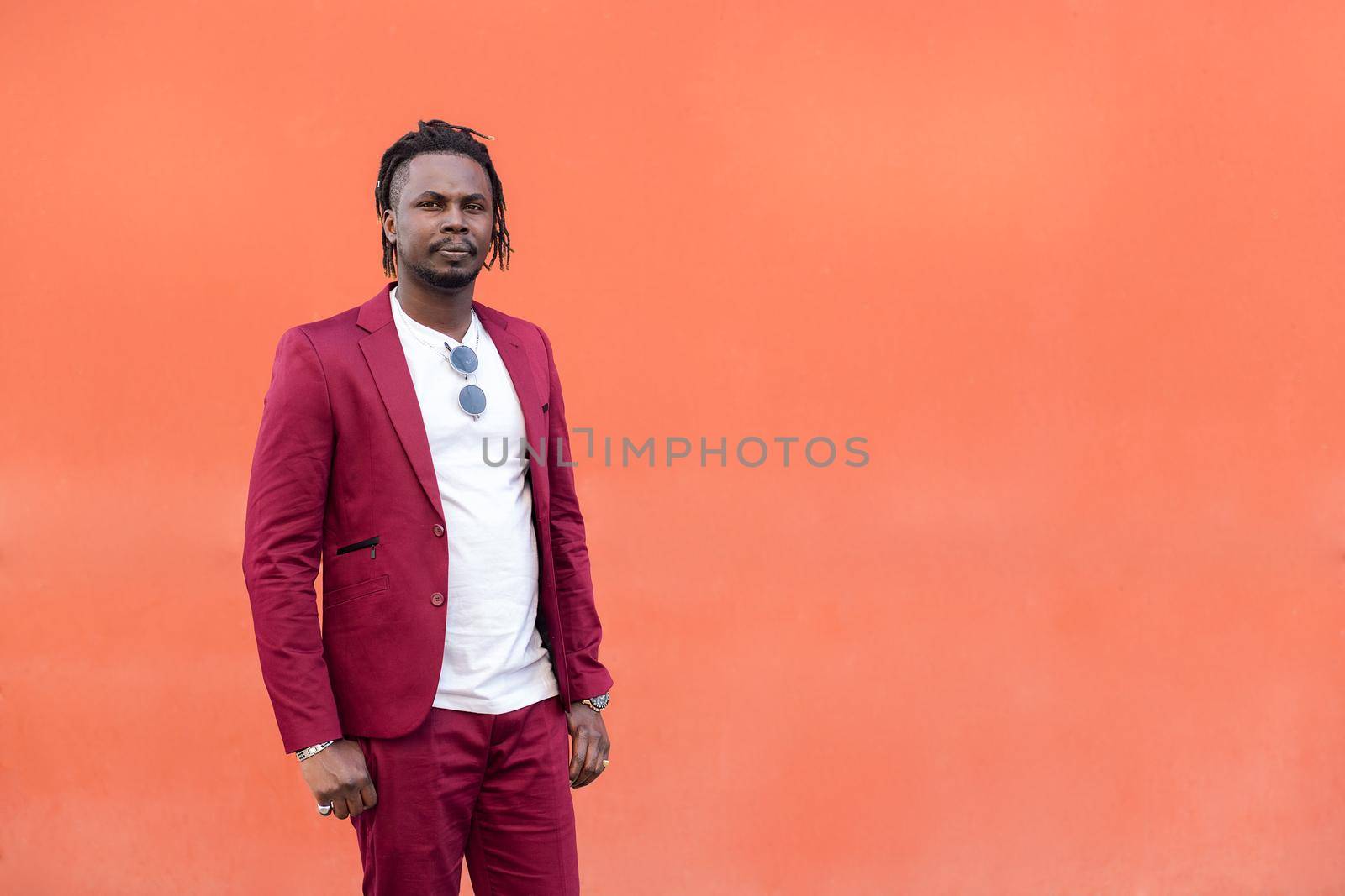 african businessman in suit with afro posing looking at camera in front of a red background, copy space for text