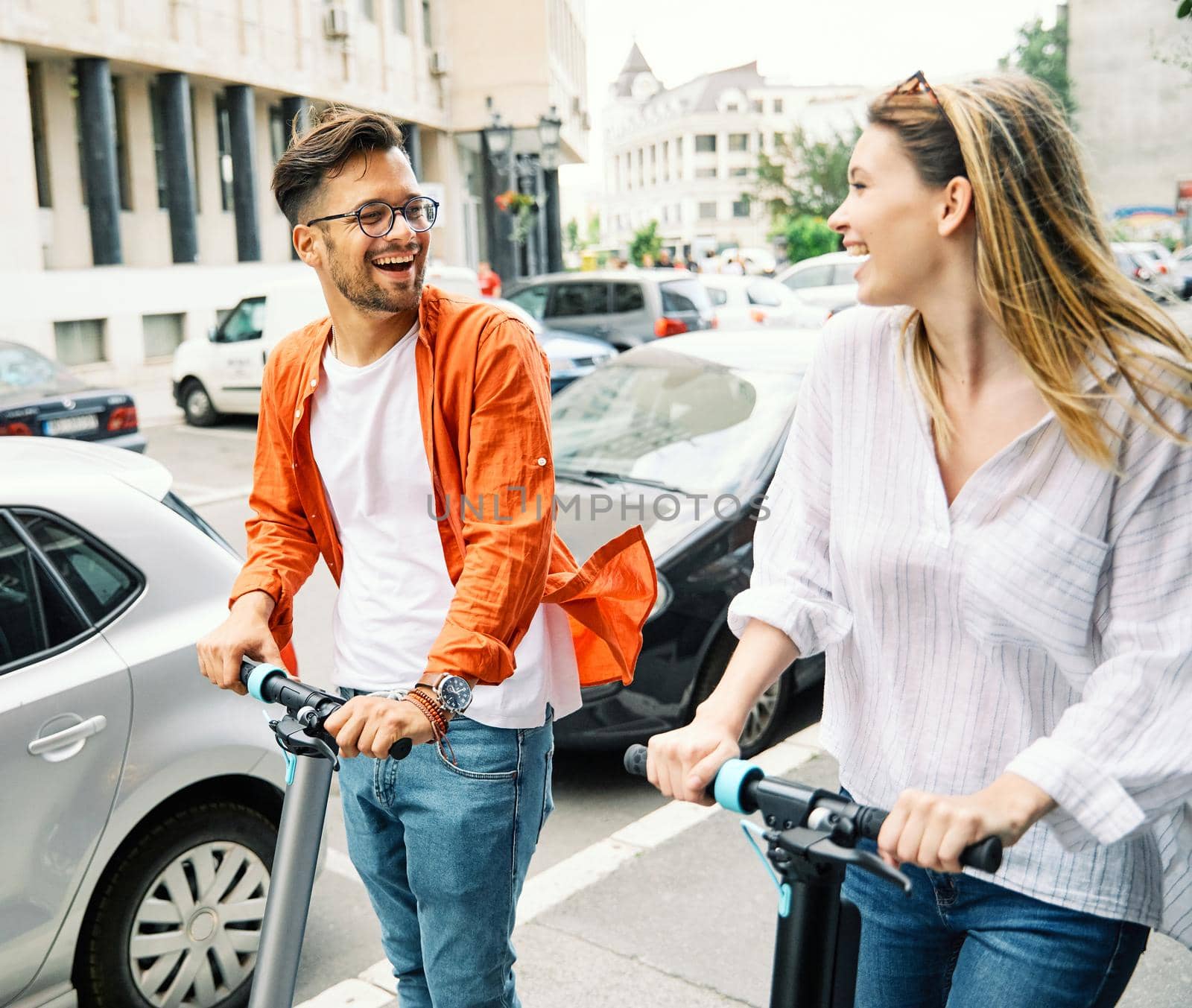 Young couple having fun driving electric scooter through the city