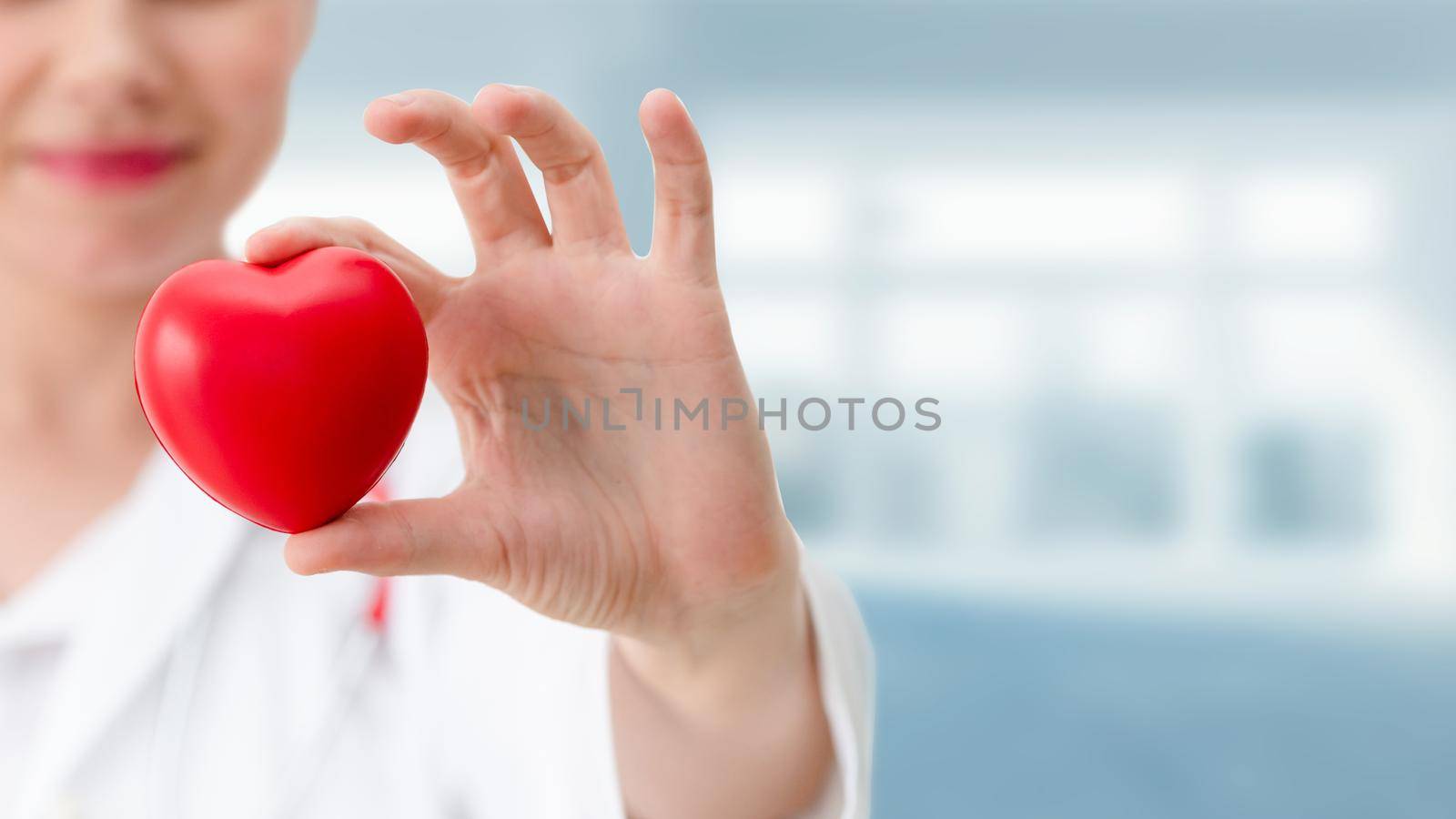 Doctor holding a red heart at hospital office. Medical health care and doctor staff service concept.