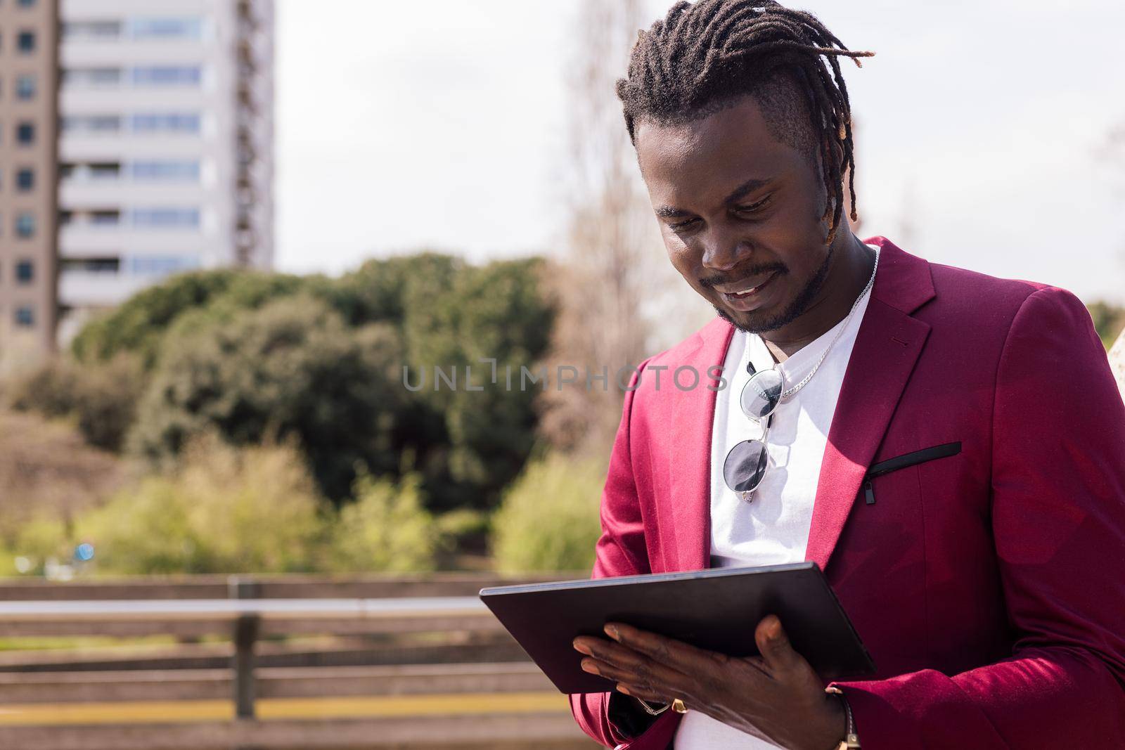 african businessman using a tablet outdoors in the city, technology and remote work concept, copy space for text