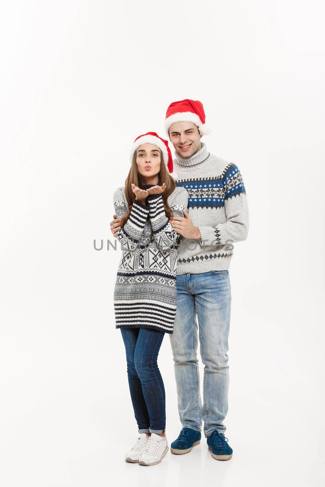 Christmas concept - Full-length Young attractive caucasian couple giving a kiss celebrating for Christmas day. by Benzoix