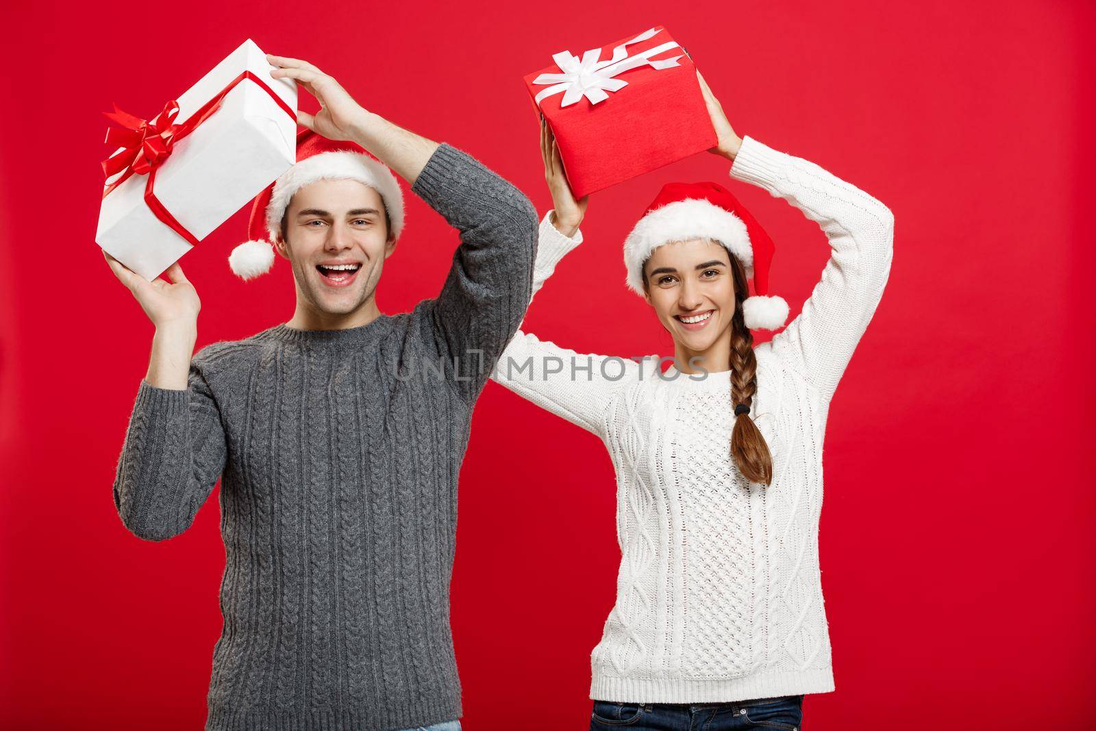 Christmas Concept - portrait young couple in Christmas sweater enjoy playing with gifts by Benzoix