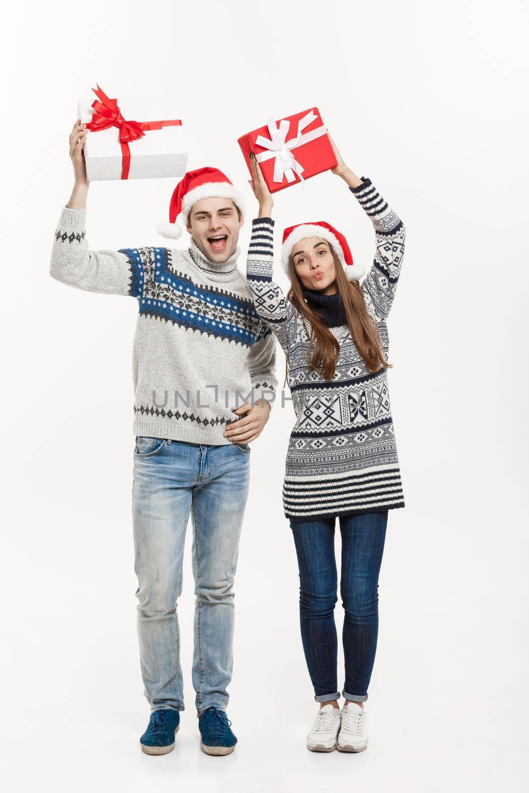 Christmas Concept - Young adorable couple holding presents isolated on white grey background