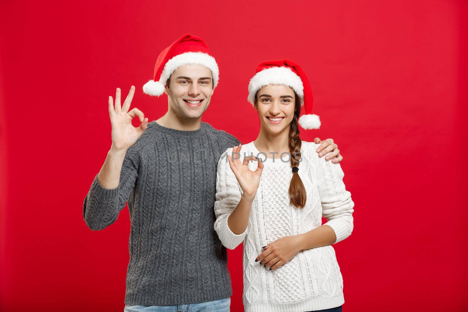 Christmas Concept - portrait lovely young couple showing ok gesture with finger to camera.
