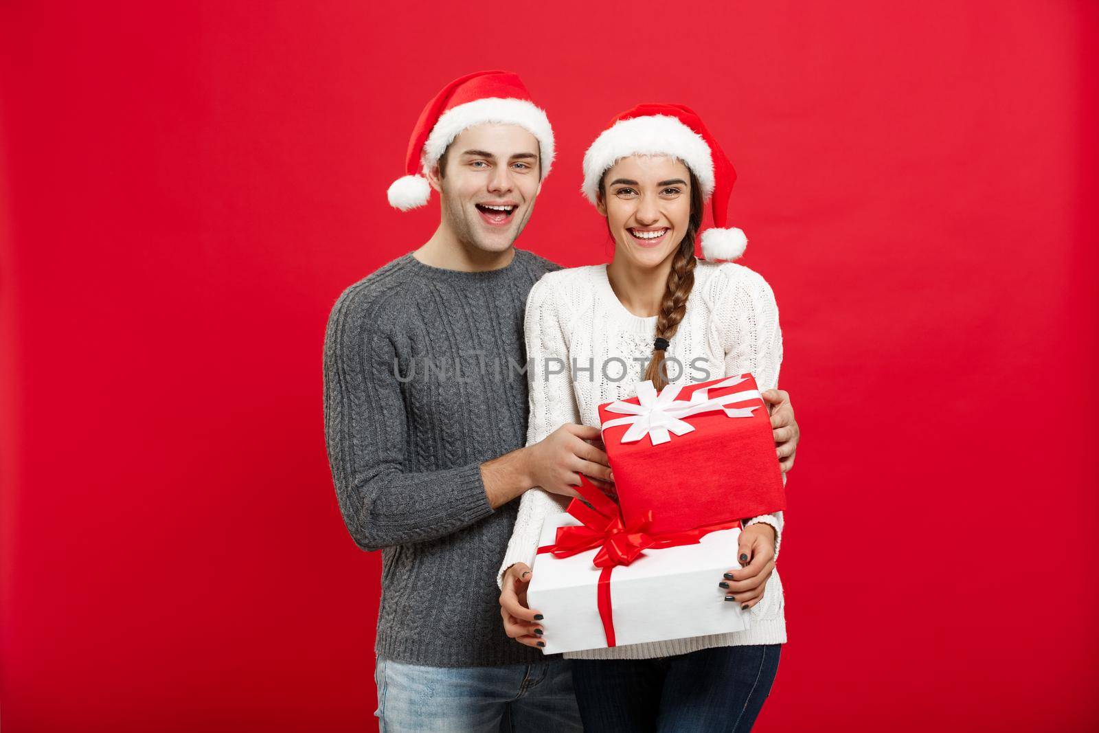 Christmas Concept - handsome young boyfriend in Christmas sweater surprise his girlfriend with gifts.