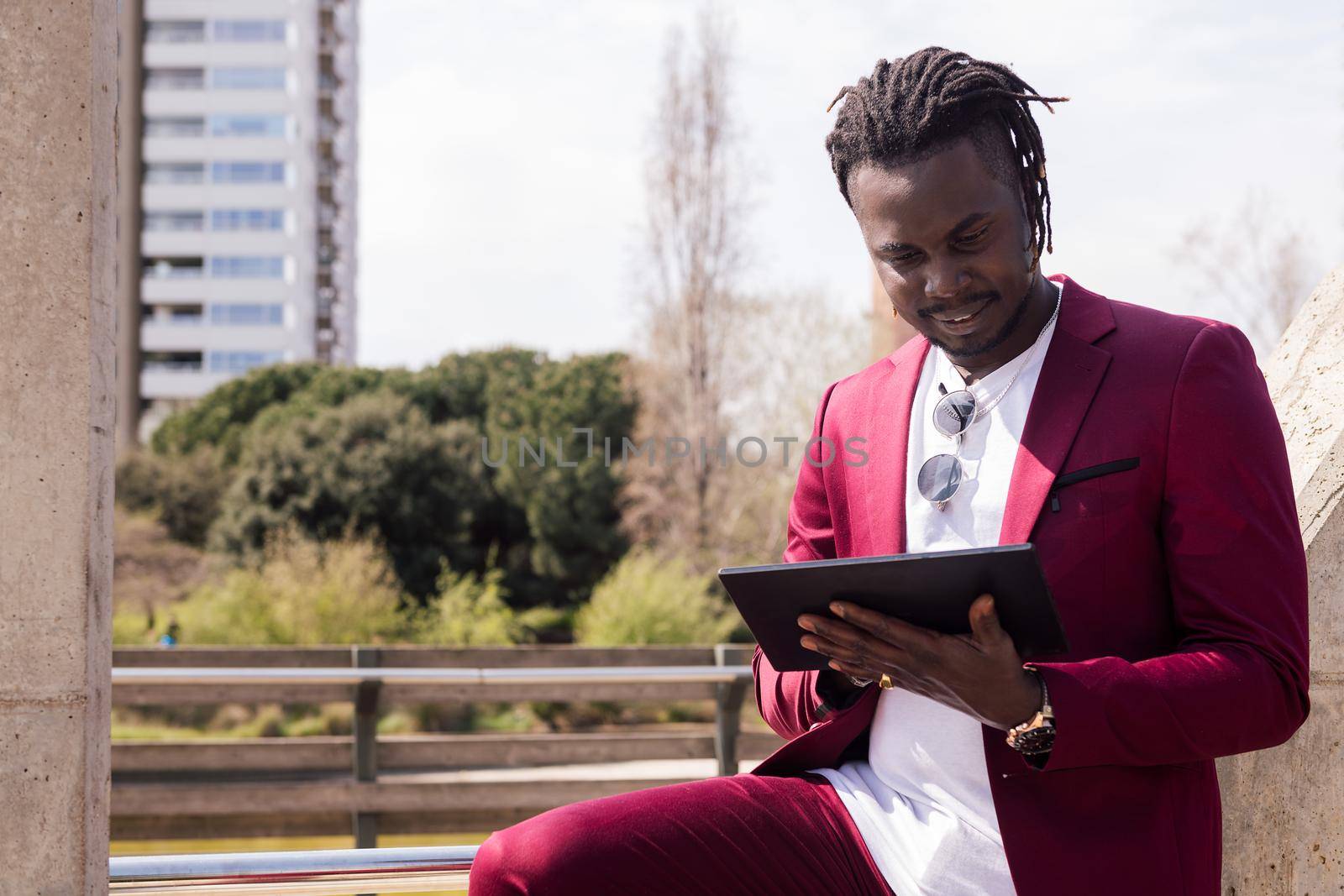 african businessman typing on a tablet outdoors in the city, technology and remote work concept, copy space for text
