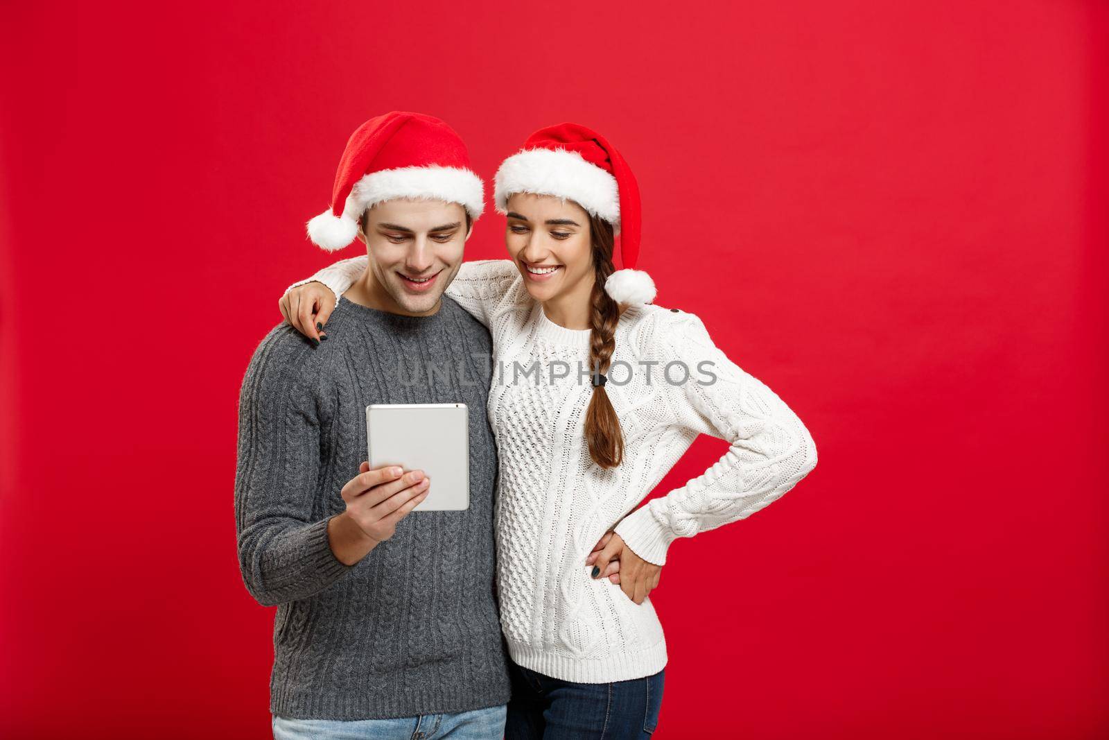 Christmas Concept - Young handsome and beautiful couple enjoy playing on tablet in christmas day by Benzoix