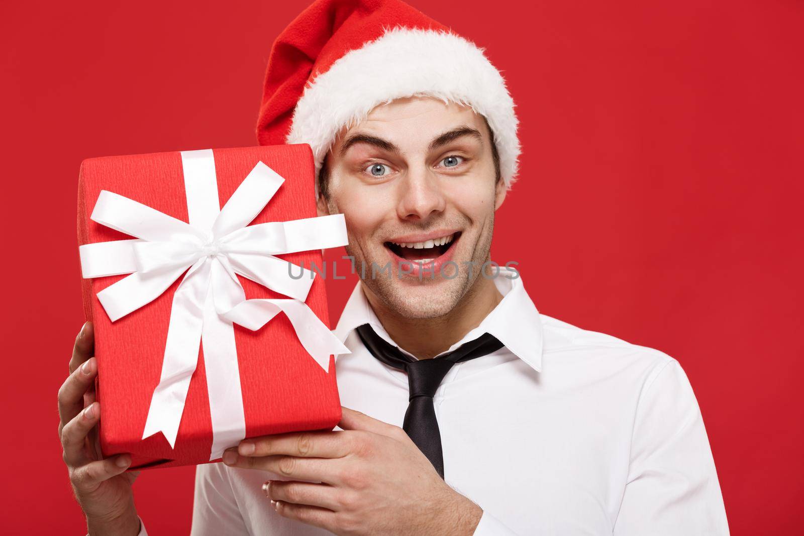 Christmas Concept - portrait close-up Santa christmas businessman over red background holding red gift. by Benzoix